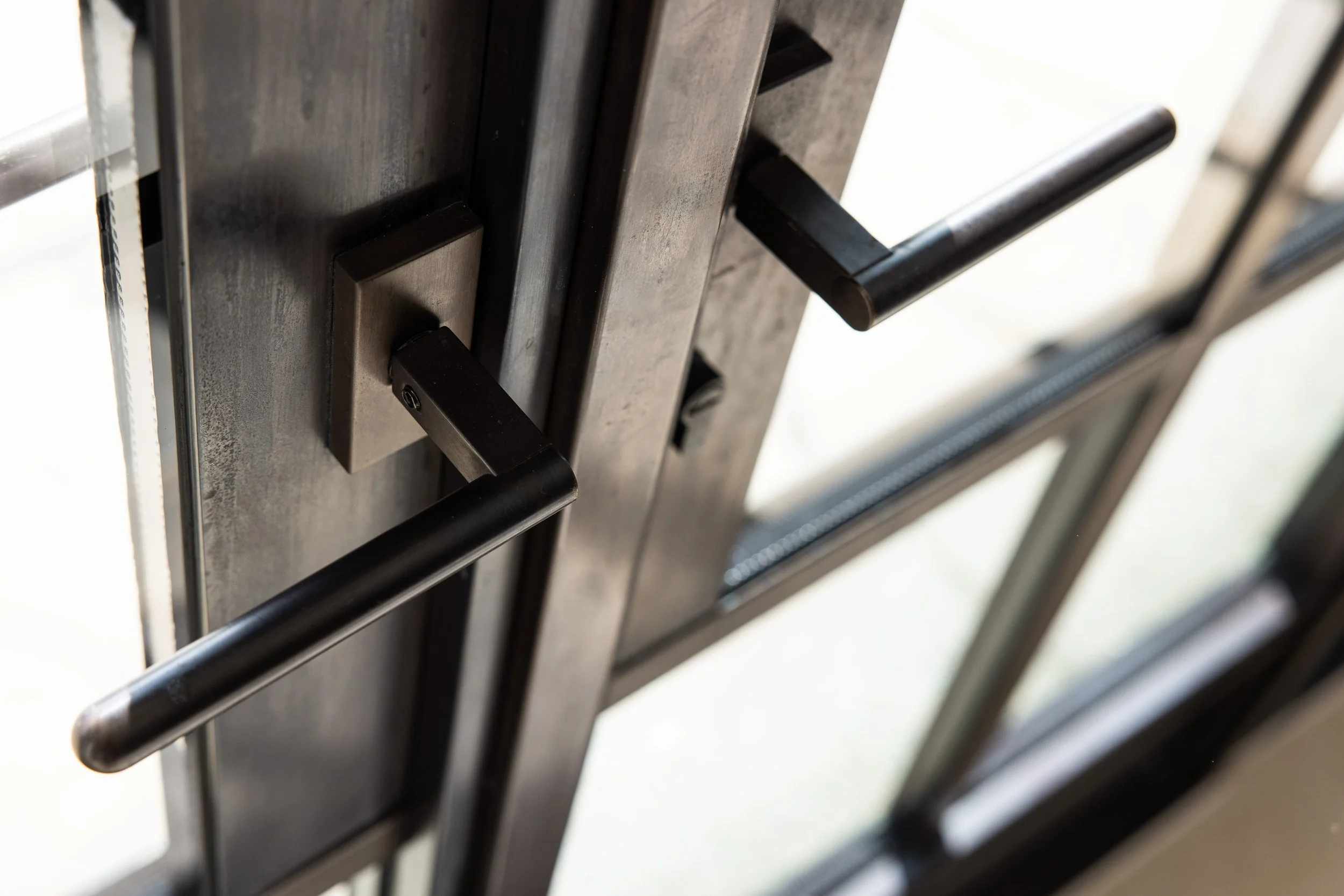 Close-up of black steel metal door handles on a glass door by Vintage Steel