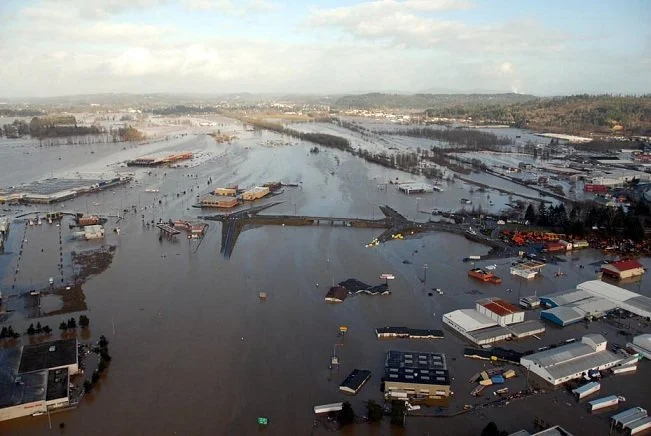 Aerial view of a city experiencing flooding, with submerged streets, buildings, and vehicles.