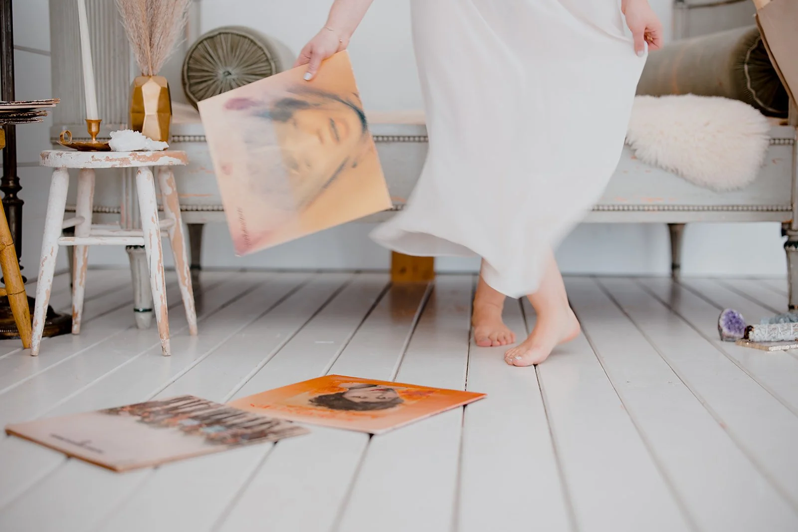 Editorial branding portrait of female brand designer dancing barefoot on a wood floor with records scattered