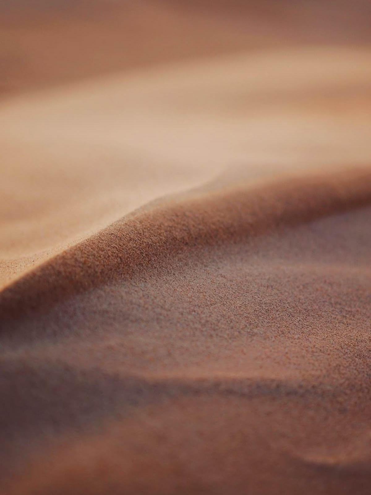 Close-up of a soft, flowing, sandy fabric or material in shades of tan and brown.