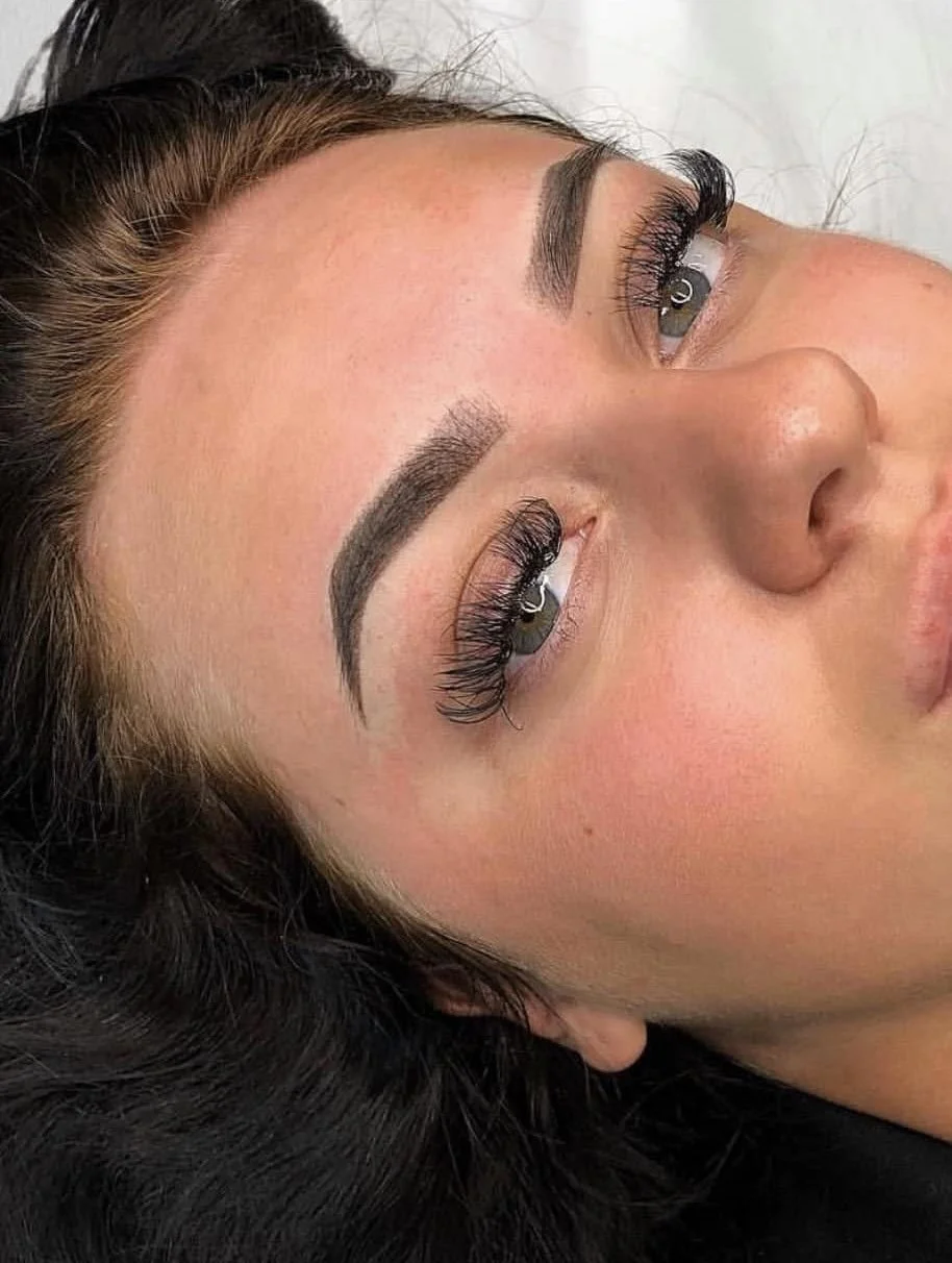 Close-up of a woman's face showing freshly done eyelash extensions and well-groomed eyebrows.