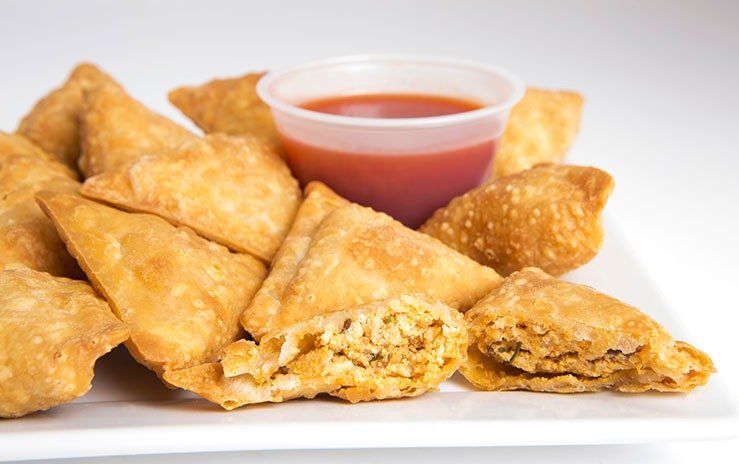 Fried chicken samosas with tamarind chutney on a white plate
