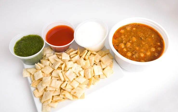 An Indian snack food Papri Chaat (Chickpea Salad) with crispy wafers topped with chickpea curry, yogurt, mint and tamarind.