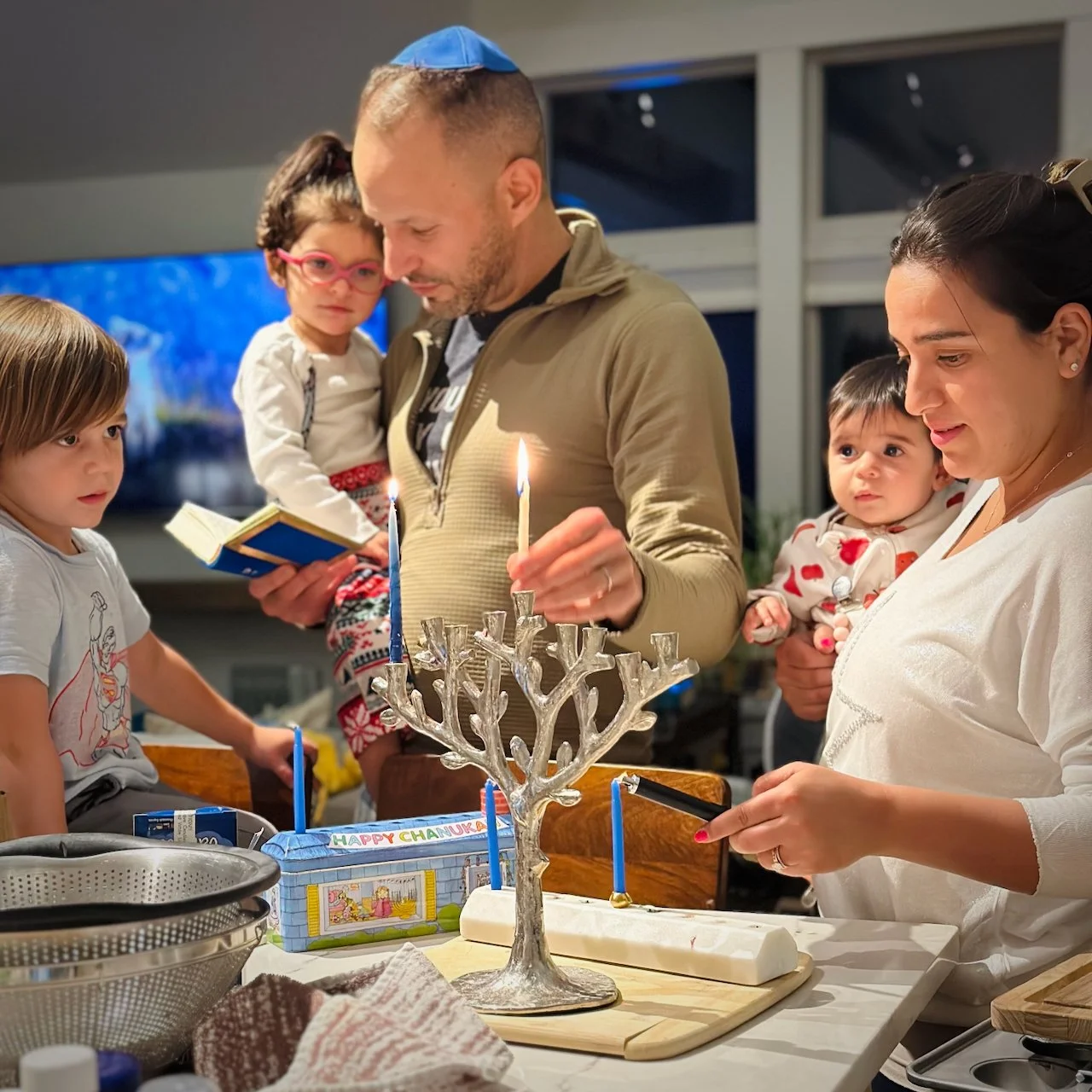Jon Estreich with his family, including his wife and three children, lighting the menorah on hanukah.