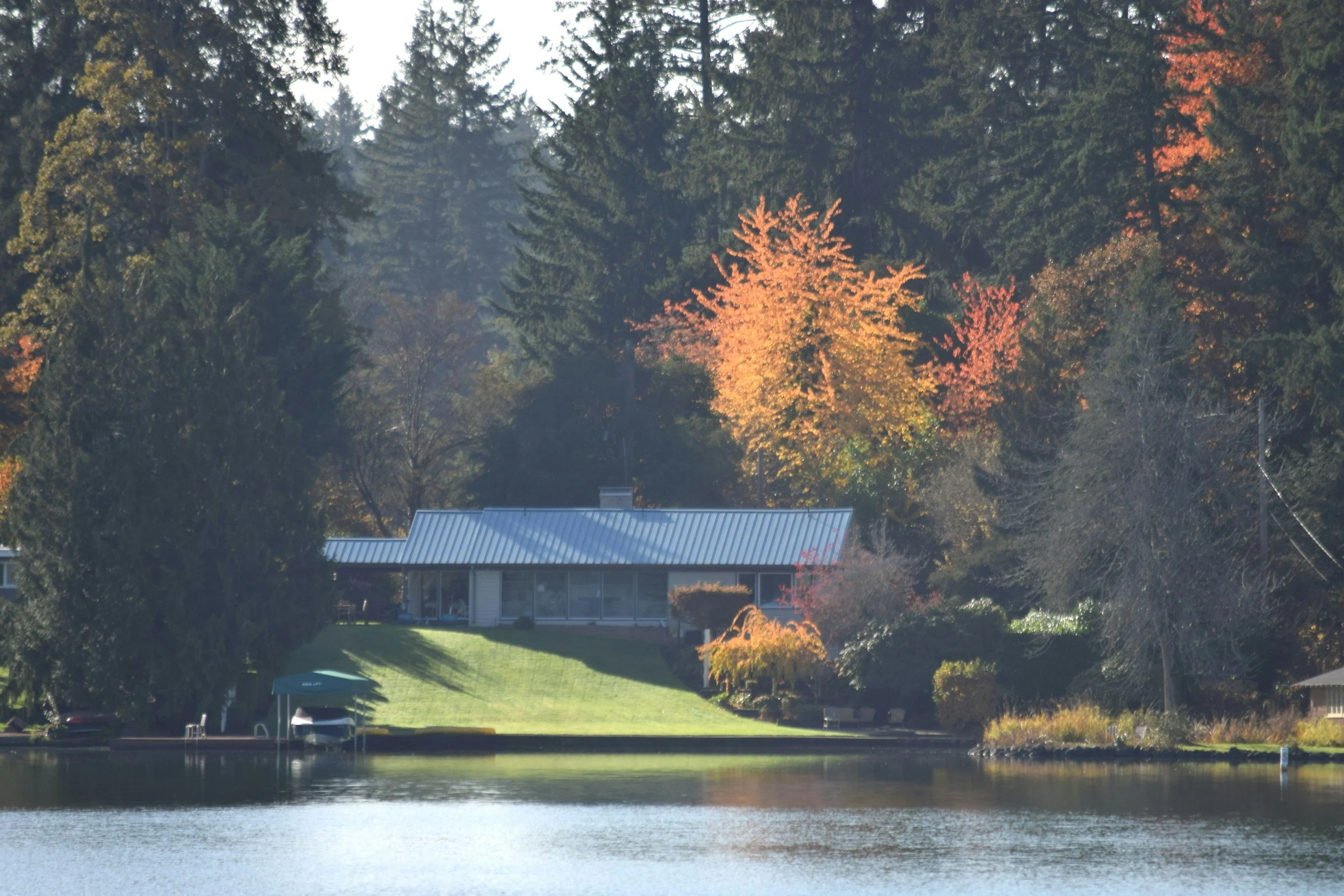 Waterfront home in Washington state surrounded by fall foliage and evergreen trees
