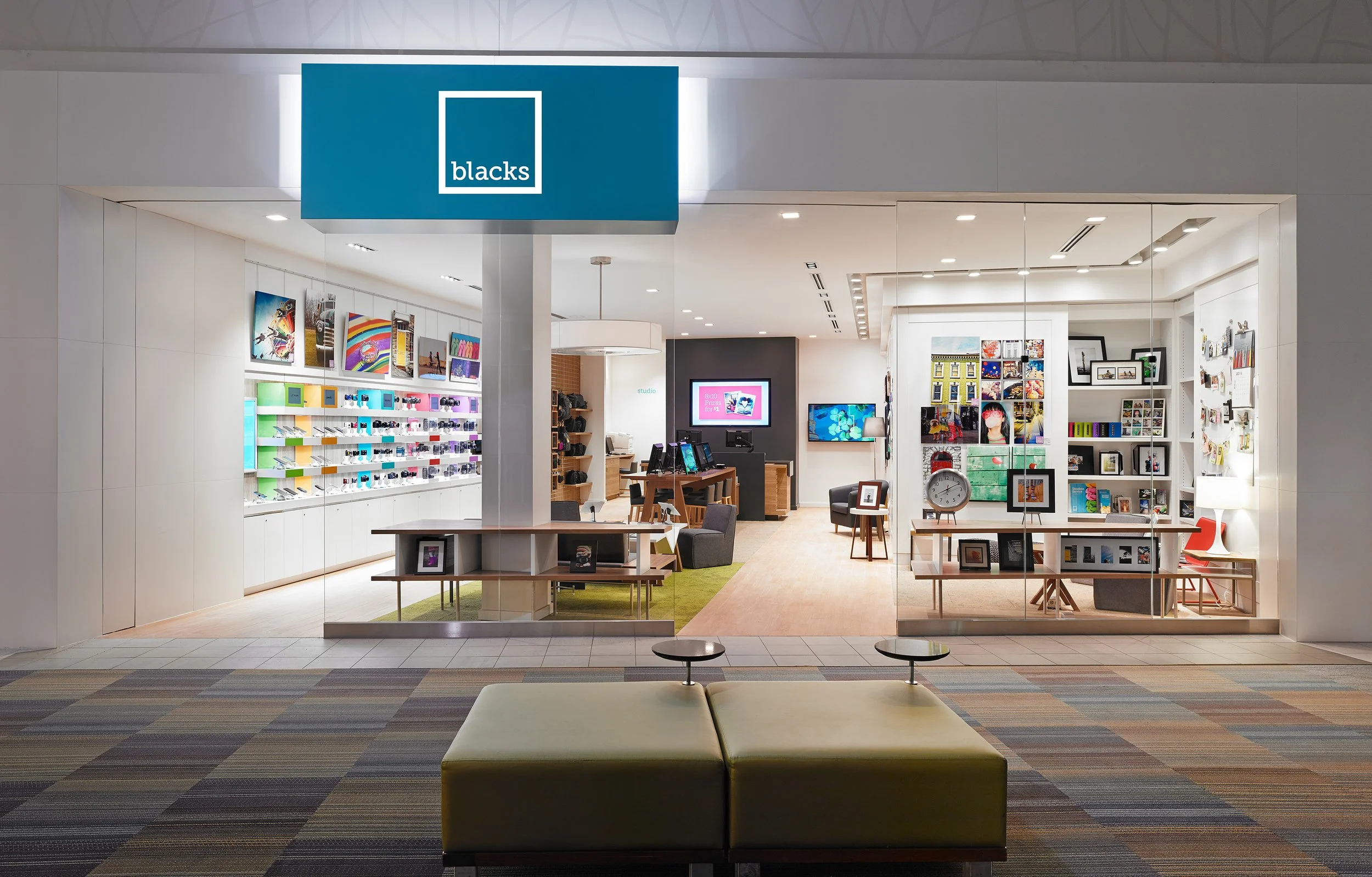 Vitrine d'une boutique d'art et de photographie avec des livres, cadres et objets de décoration, vue de l'extérieur dans un centre commercial.