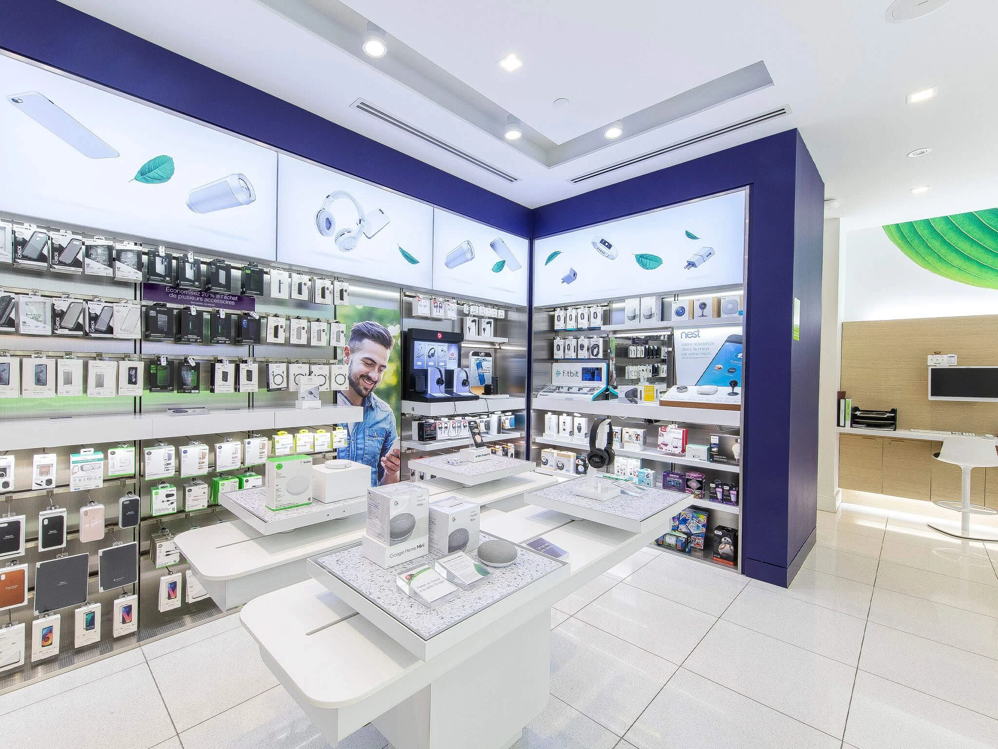 Vitrine d'un magasin d'électronique avec des appareils en vente, cellules d'affichage modernisées, et un homme souriant regardant un téléphone portable, mettant en évidence les produits technologiques