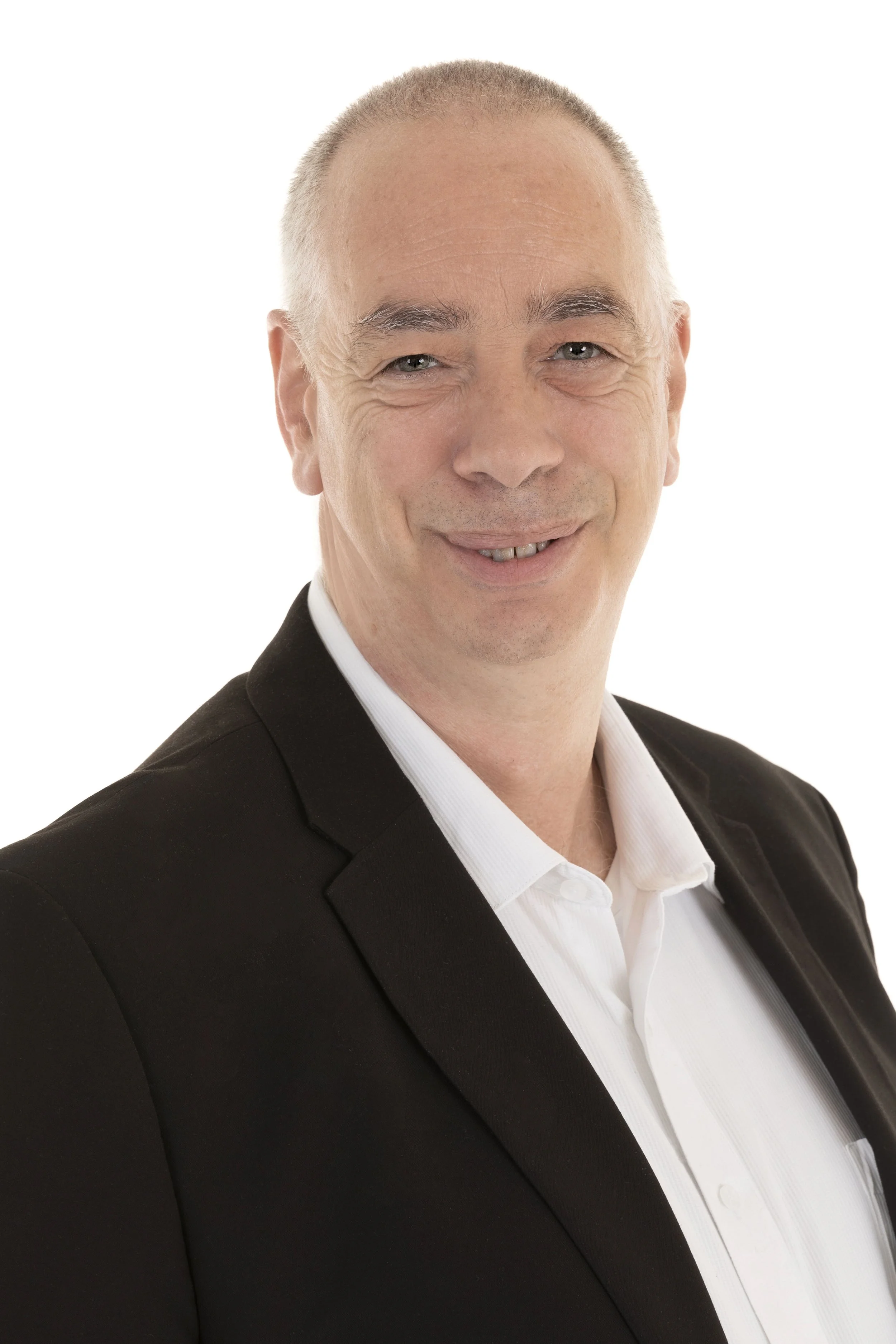 A middle-aged man with short gray hair, wearing a black suit jacket and white collared shirt, smiling.