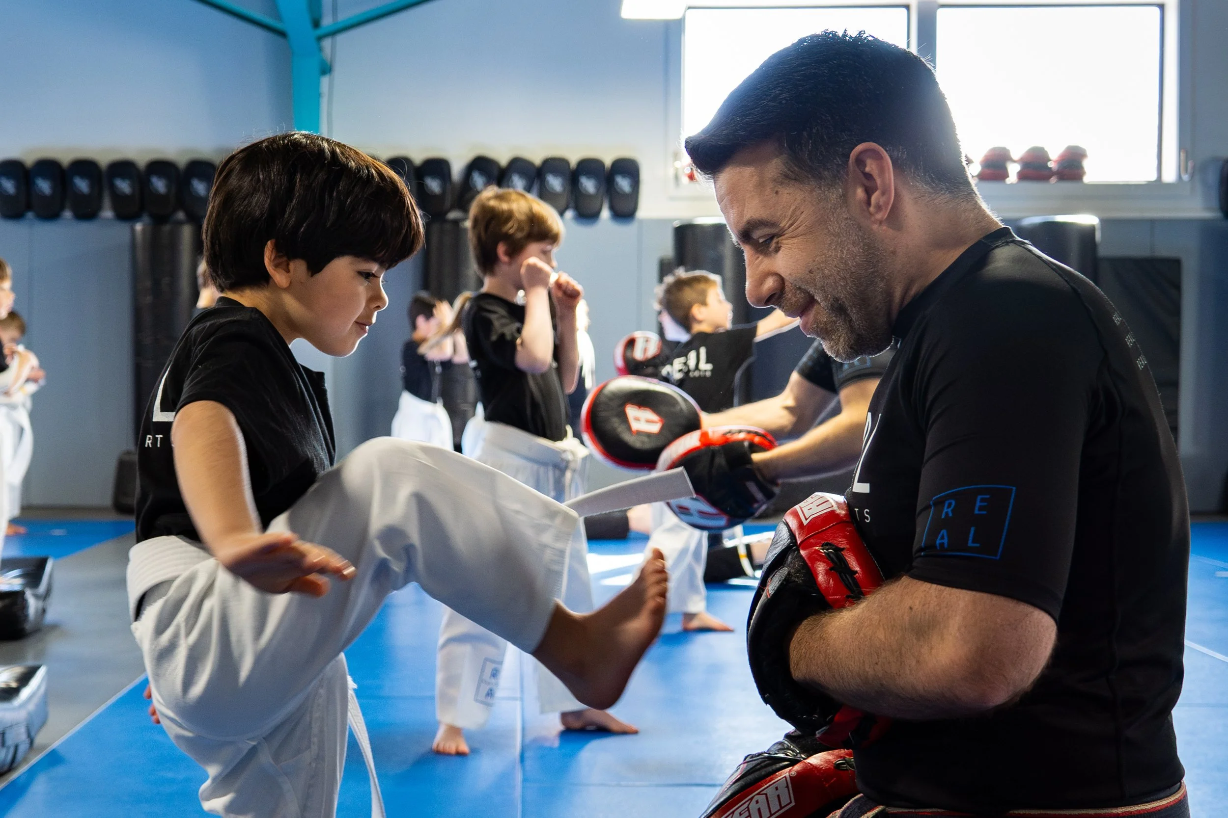 Little Dragon Martial Artist kicking pad held by coach