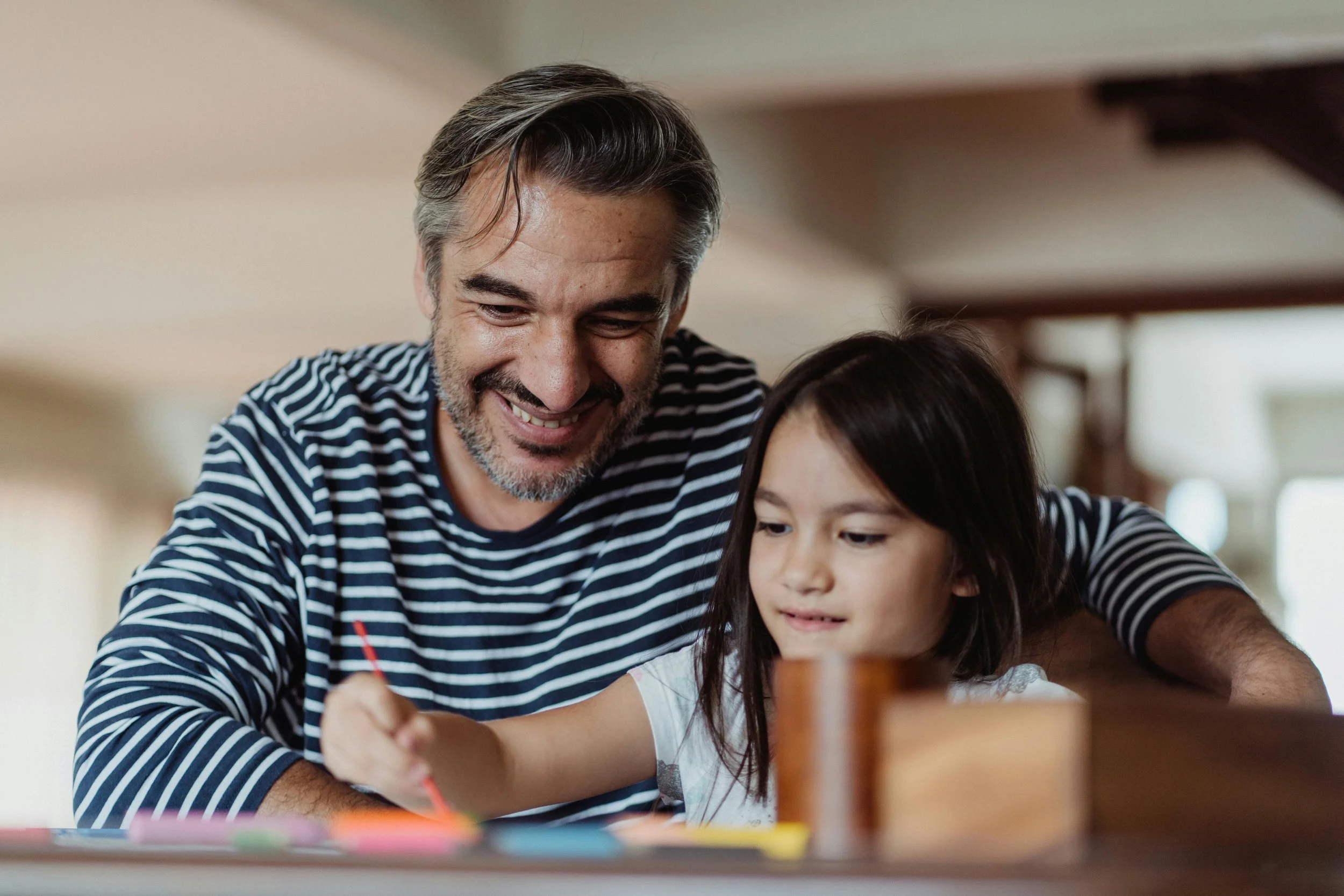 A confident and relaxed father feeling more in control of ADHD, autism, and PDA helping daughter with school work.