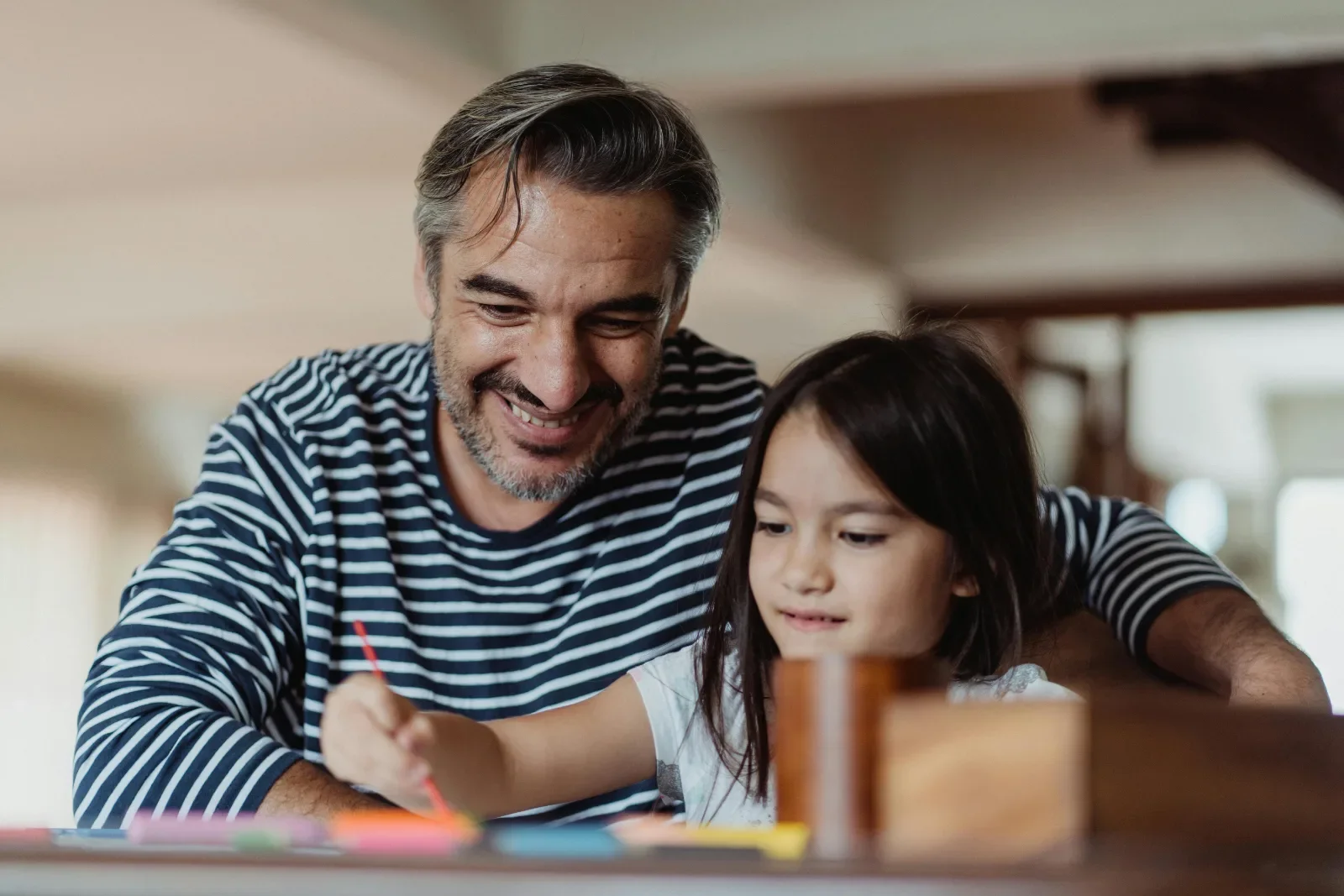 A confident and relaxed father feeling more in control of ADHD, autism, and PDA helping daughter with school work.