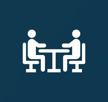 Icon of two people sitting at a table facing each other, exchanging items.