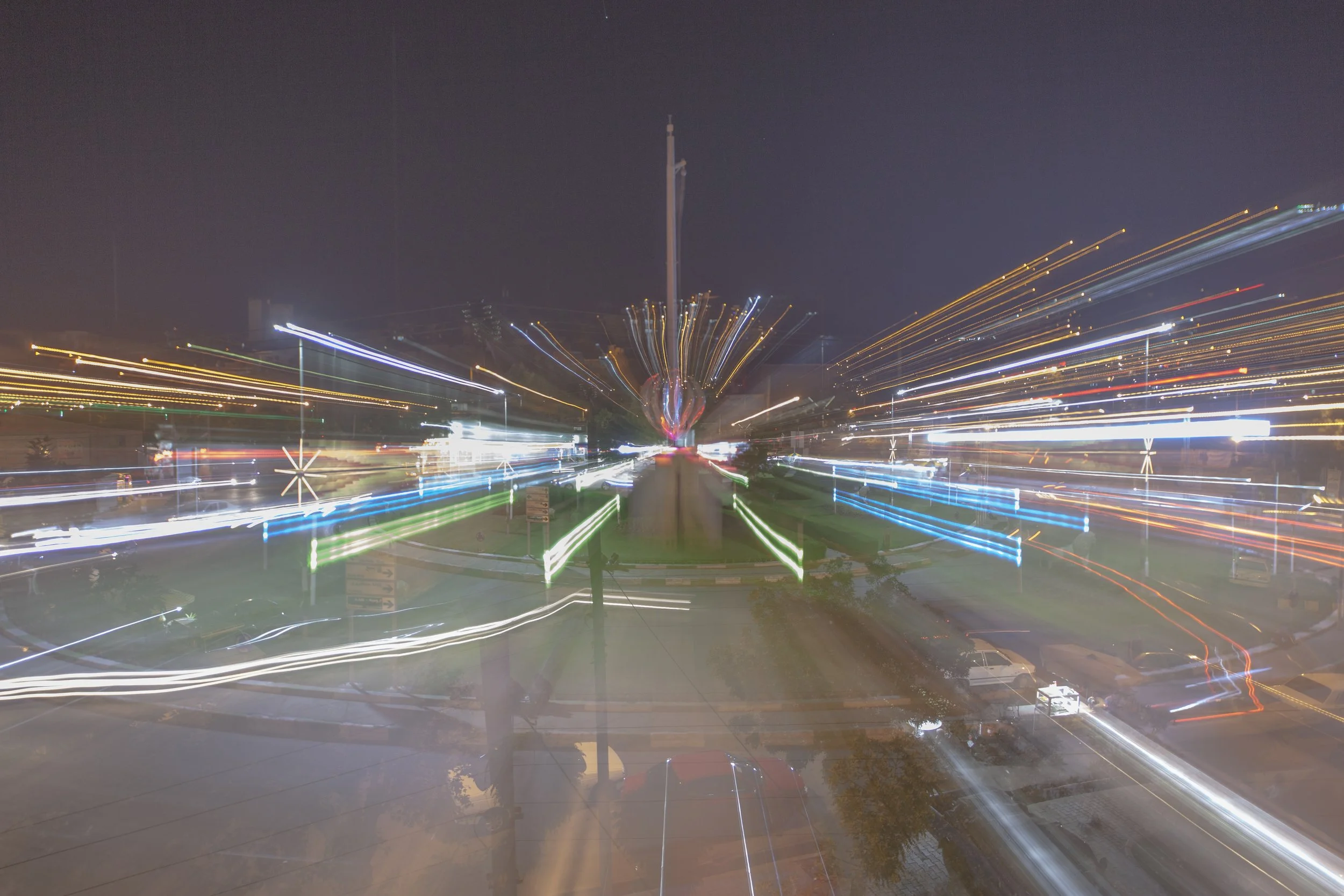 Nighttime cityscape with lights creating streaks, possibly a long exposure shot of a busy street or festival