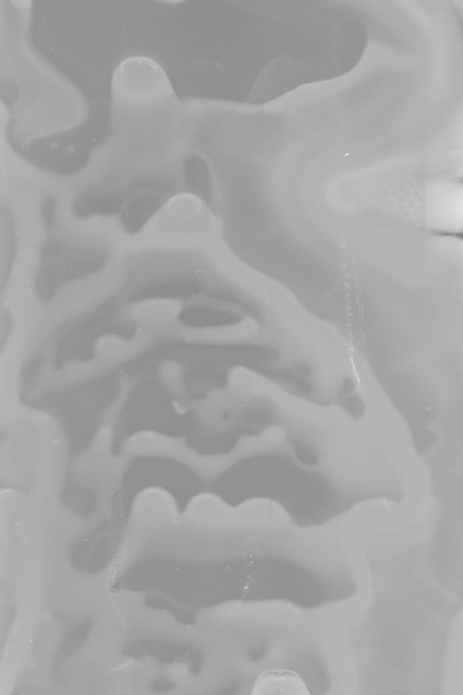 Close-up of a transparent surface with an abstract, distorted image behind it, possibly a face.