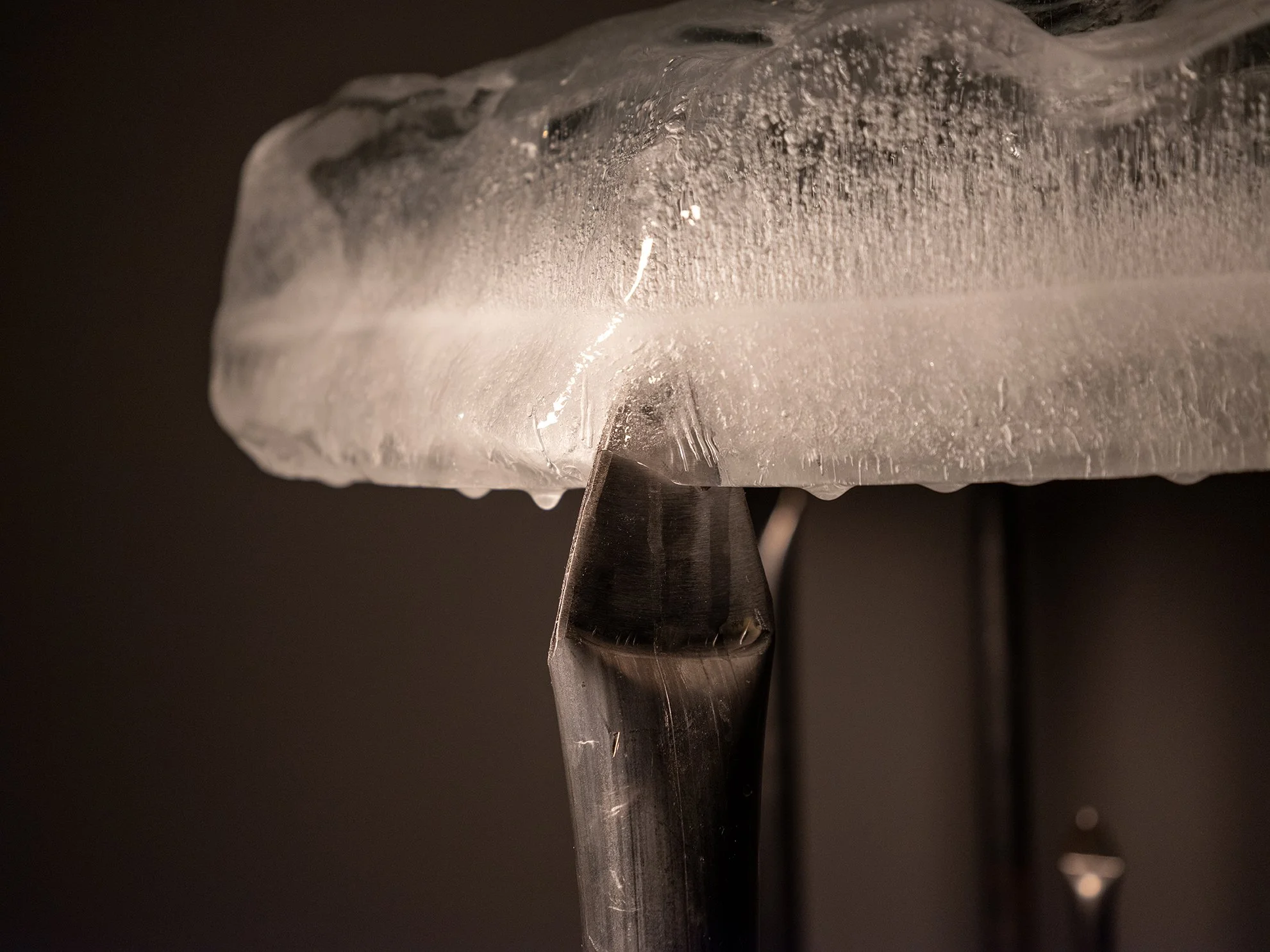 Close-up of an ice sculpture with a chisel in front of a black background.