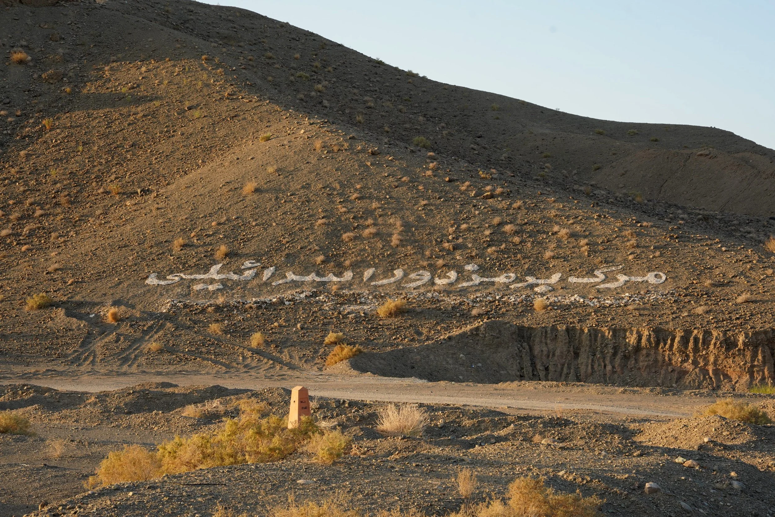 Desert hillside with the words 'Sister City' spelled out in rocks on the slope.
