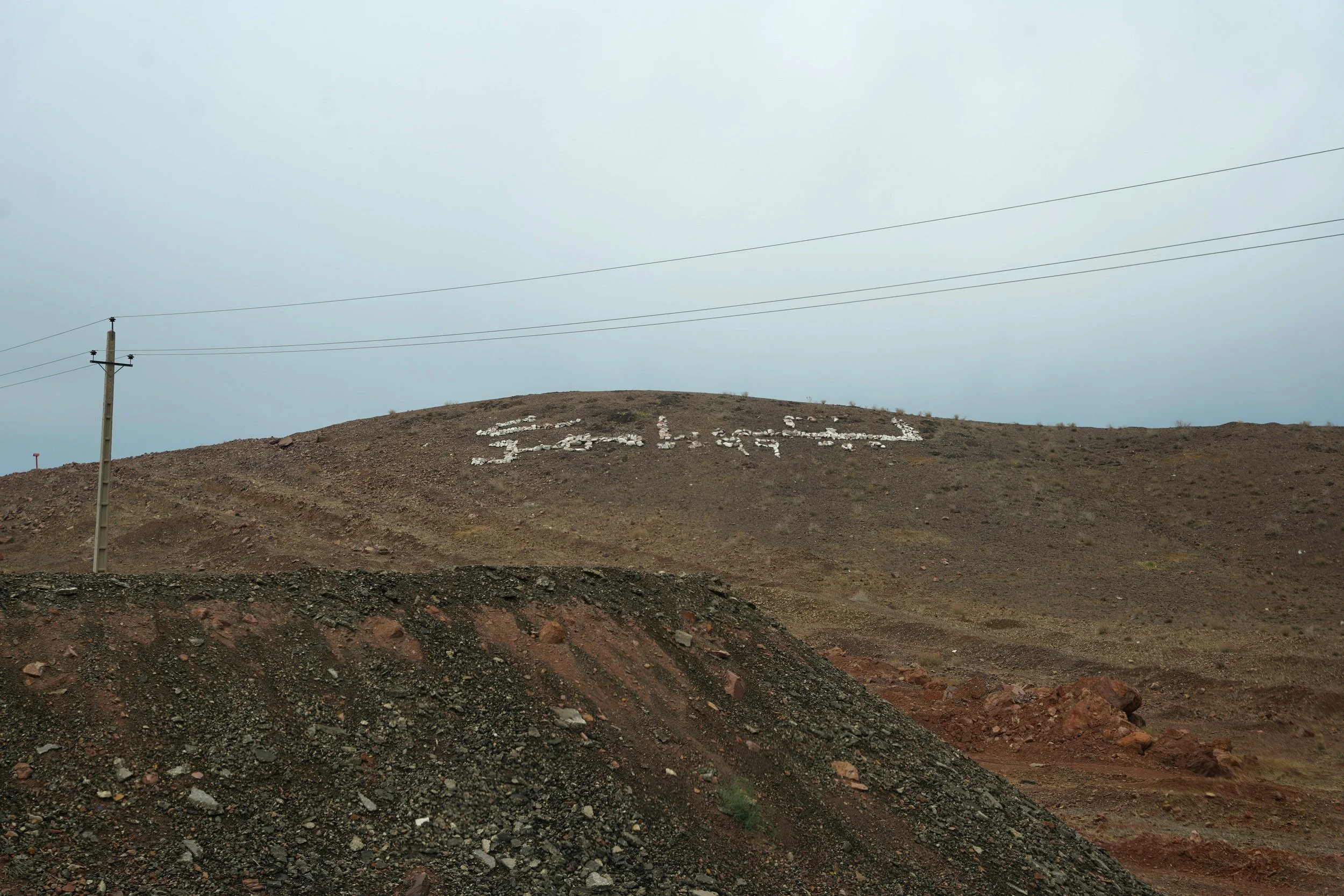 A desert landscape with a hill displaying the word 'LOVE' spelled out in white rocks.