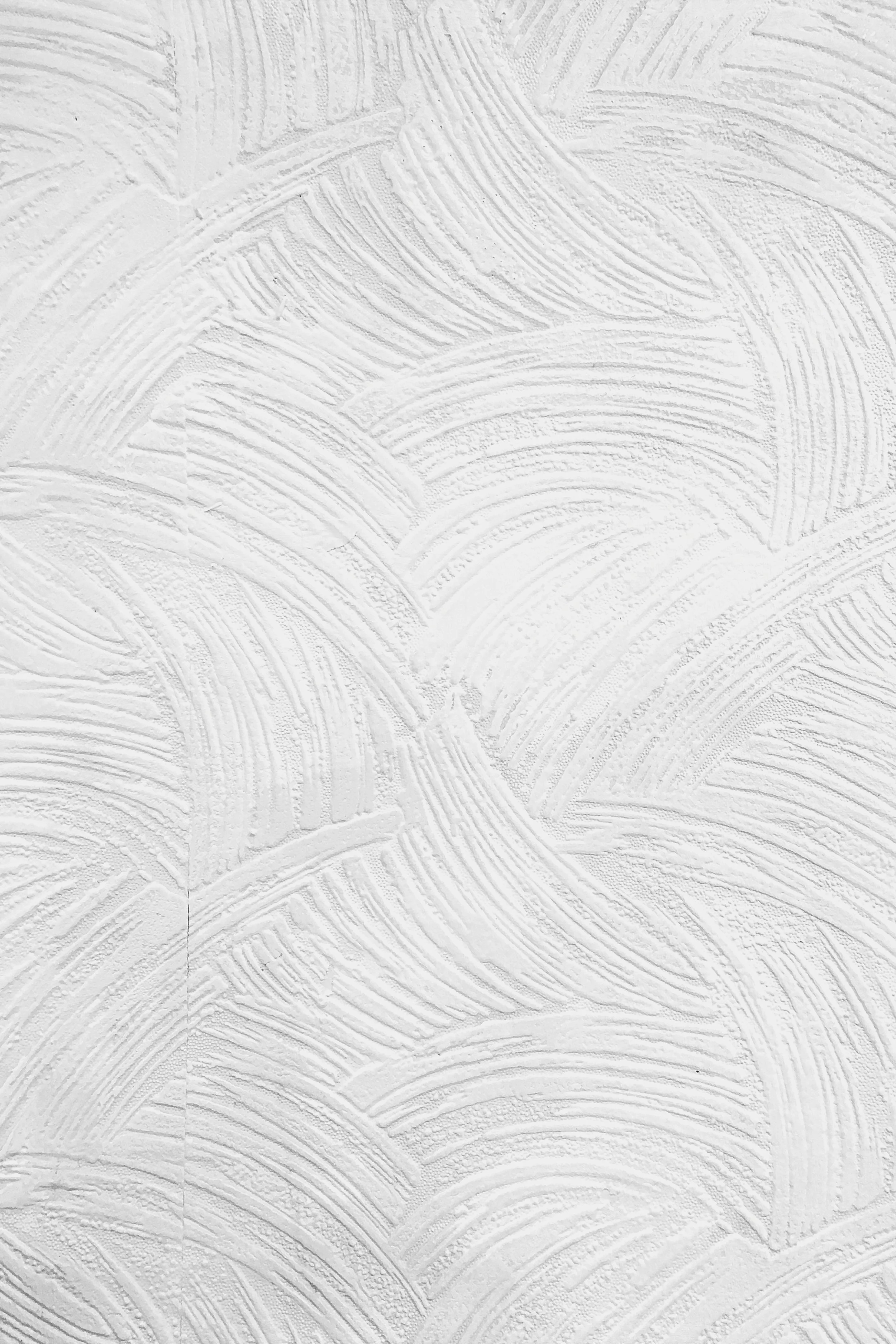 Close-up of a textured white wall with an abstract pattern of curved, overlapping brush strokes or plaster markings. Elevated Accounting Canada Cindy Kumar Brand Asset decor.