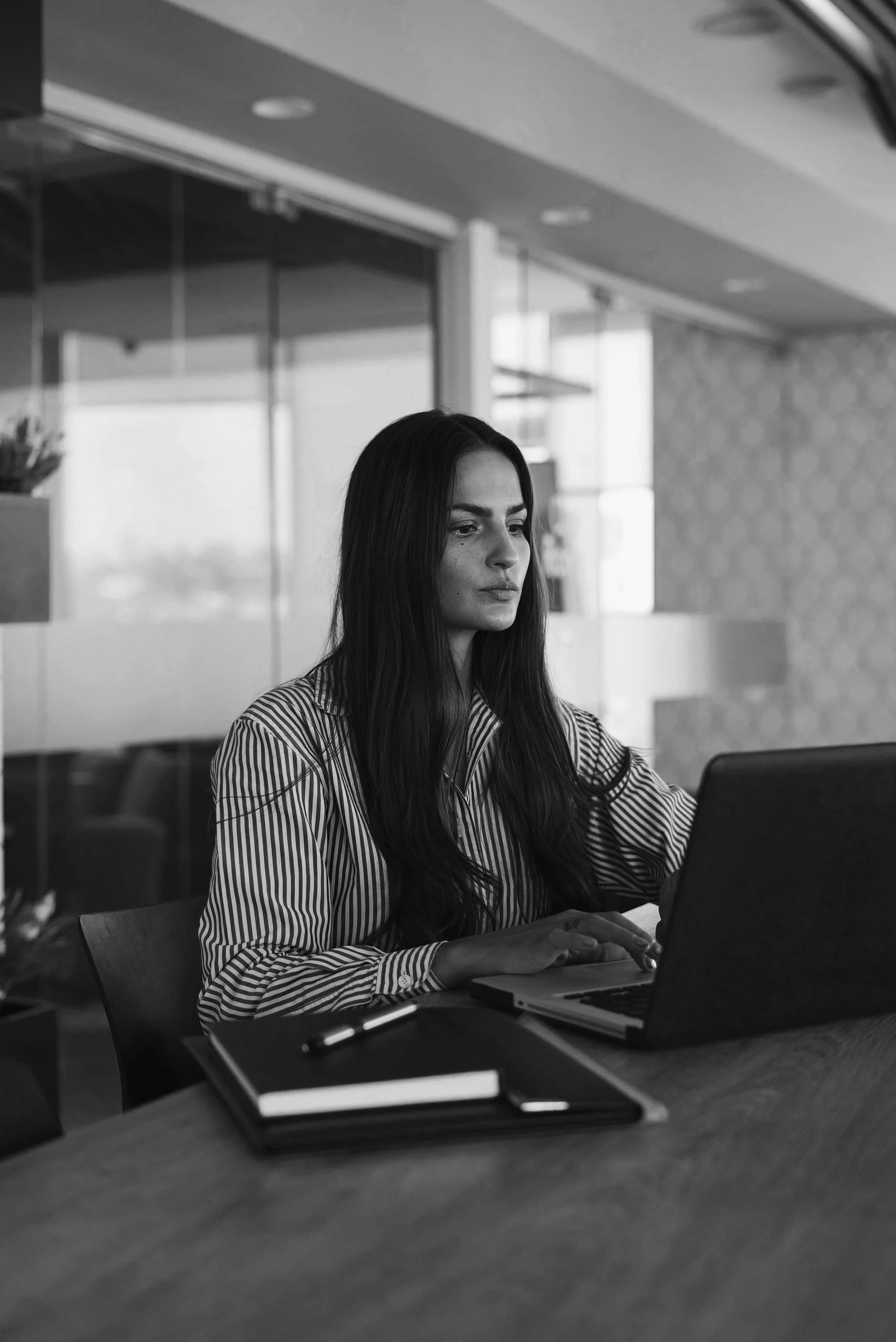 Professional woman in a striped shirt working at a laptop — black and white editorial brand image, Elevated Accounting CFO on Call