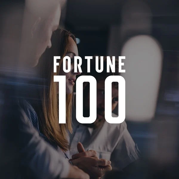 People working together with the text 'Fortune 100' overlayed in the foreground.