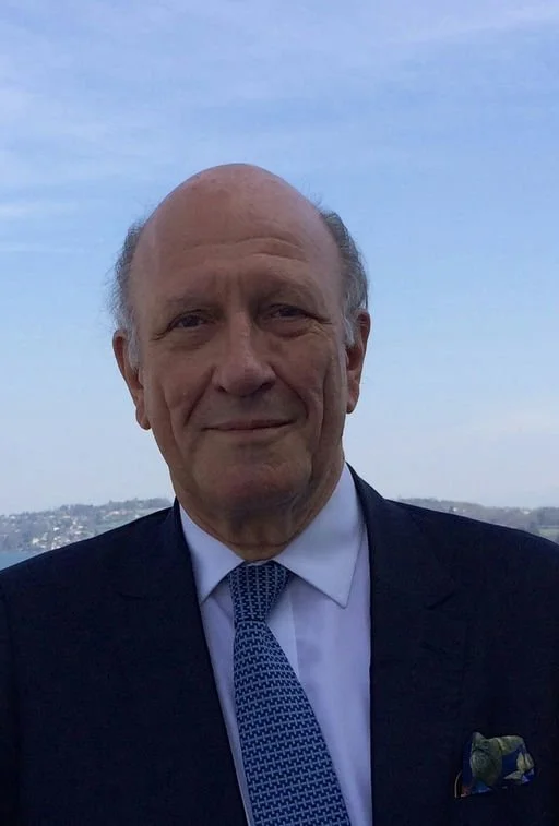 Head and shoulders of a man facing the camera in suit and tie.
