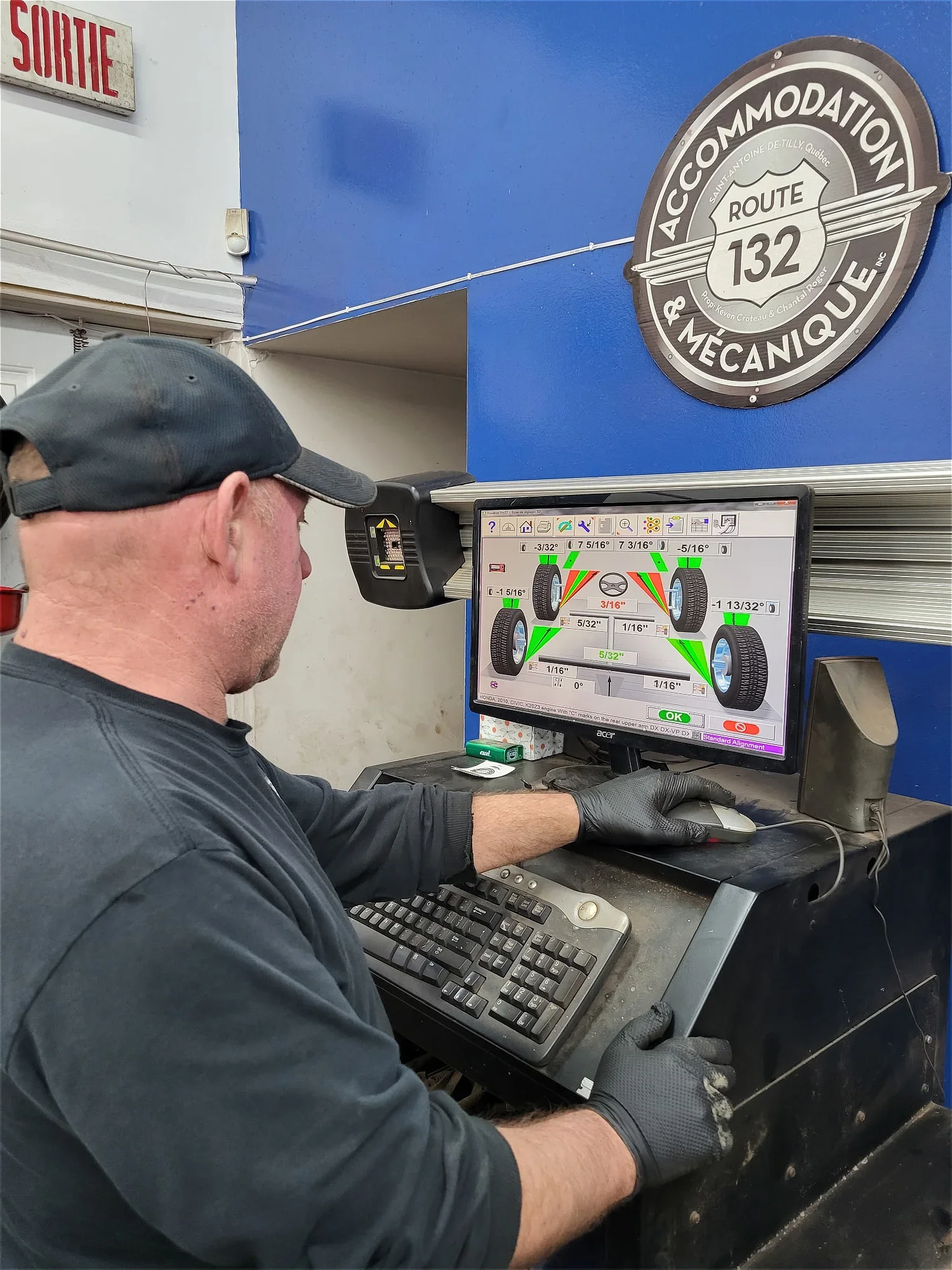 Un technicien effectue un alignement des roues d'une voiture à l'aide d'un ordinateur avec un logiciel de diagnostic.