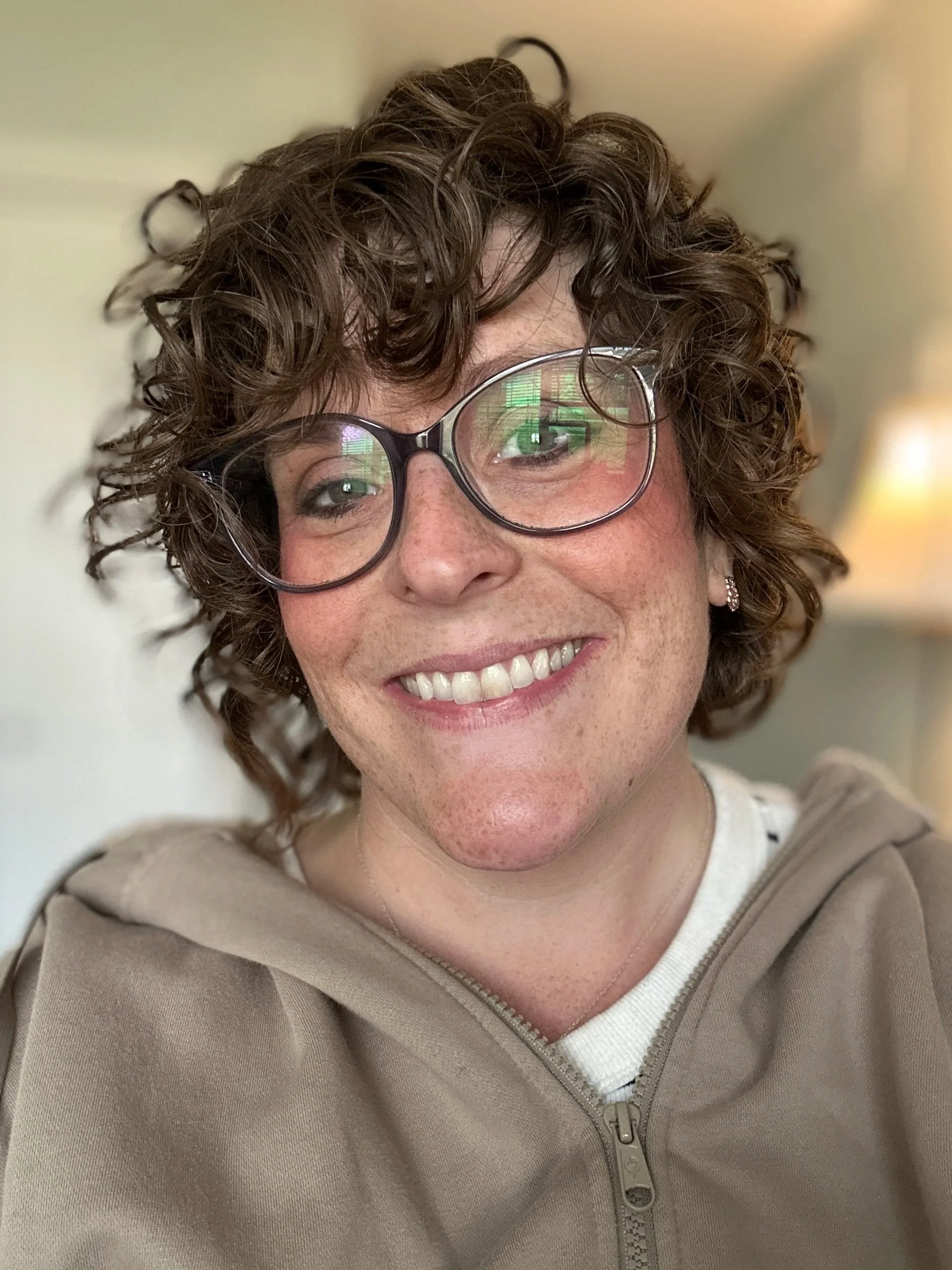 Photo of a smiling adult woman wearing glasses, facing the camera.