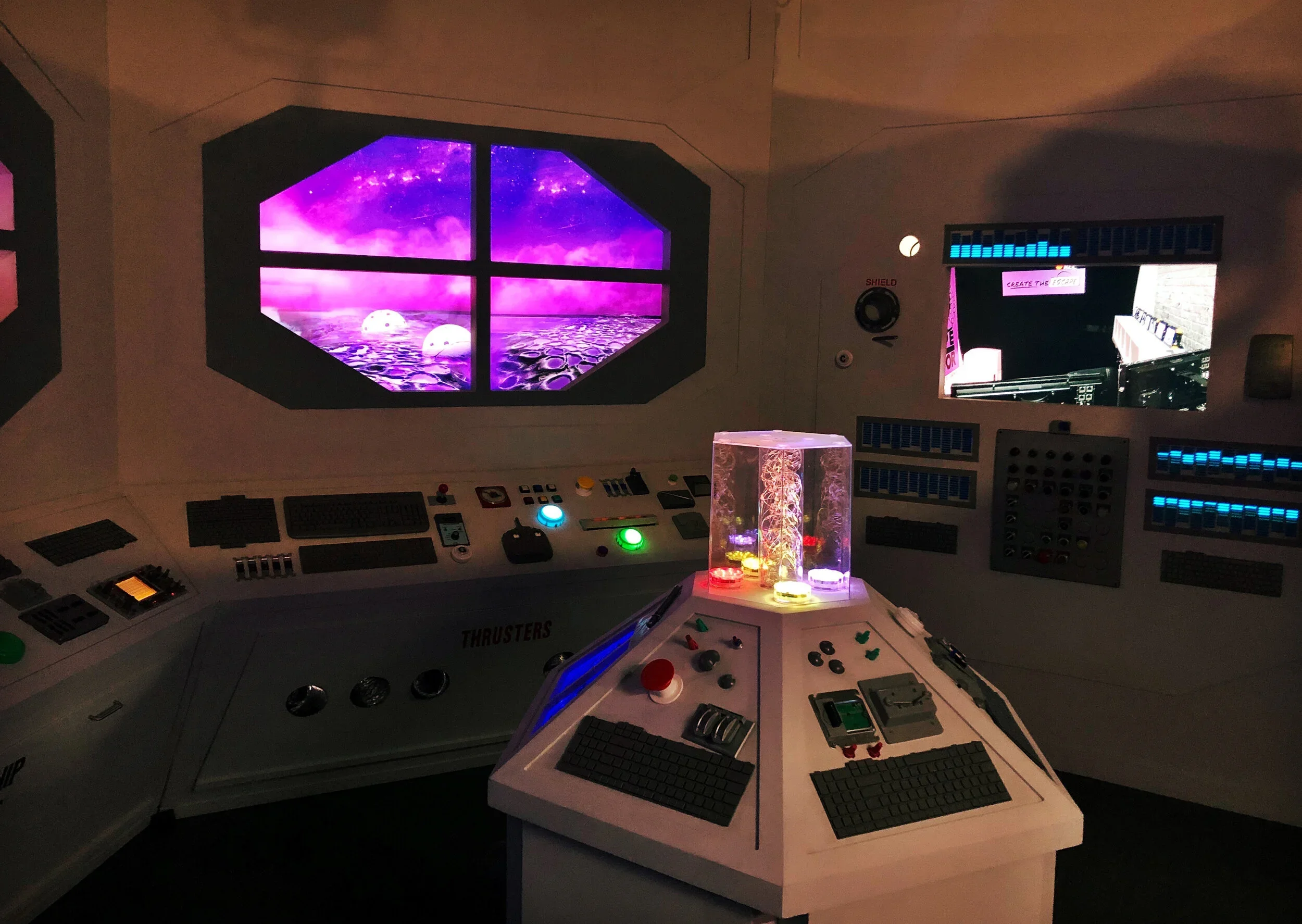 Futuristic spaceship bridge with control panels, colorful lights, and a large window showing a cosmic landscape with purple and pink sky and moons.