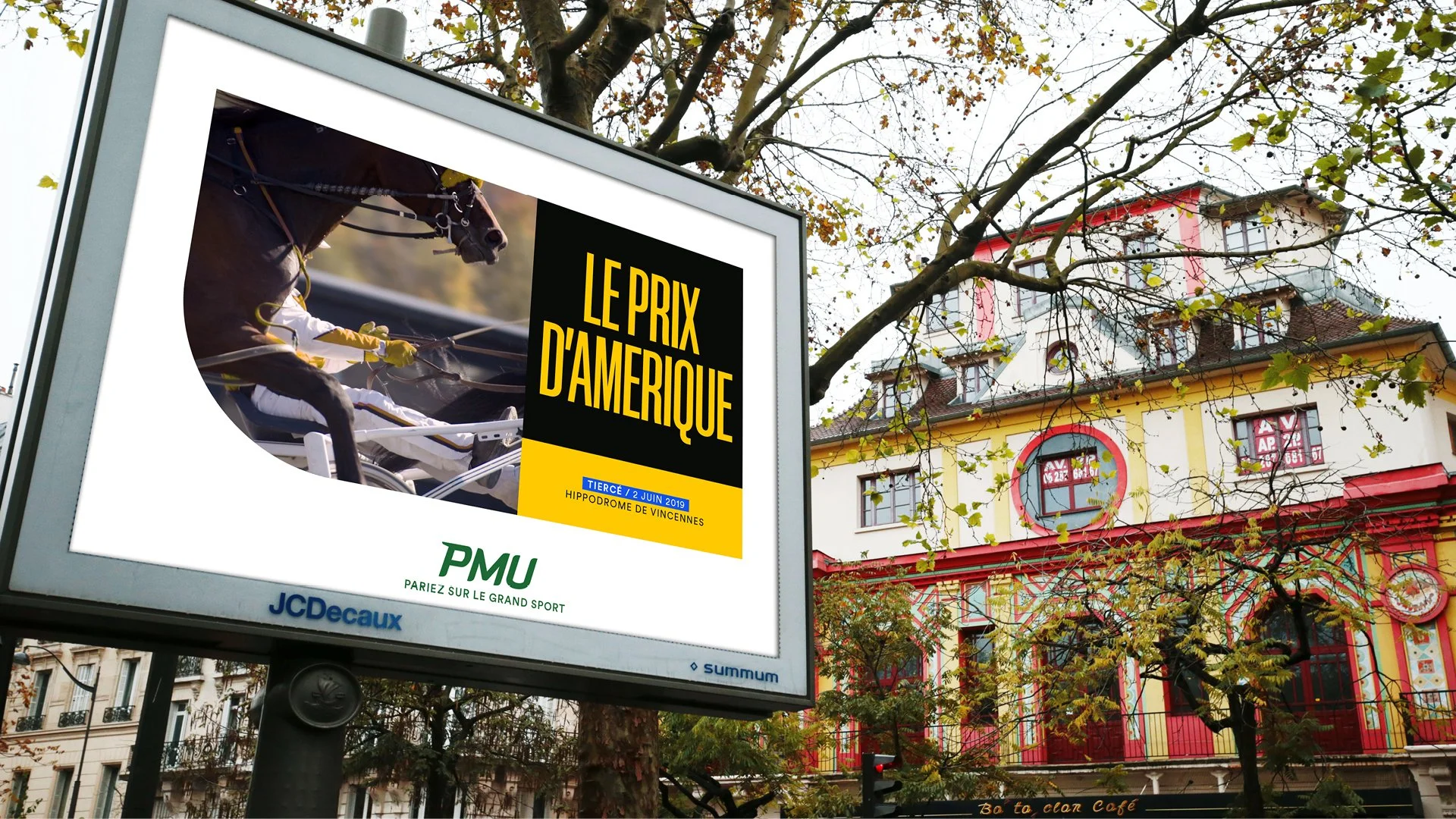 Panneau d'affichage publicitaire annonçant le prix d'Amérique, avec une image de chevaux de course, affichant la date 2 juin 2019, à Vincennes, Paris, avec des bâtiments colorés et des arbres à l'automne en arrière-plan.