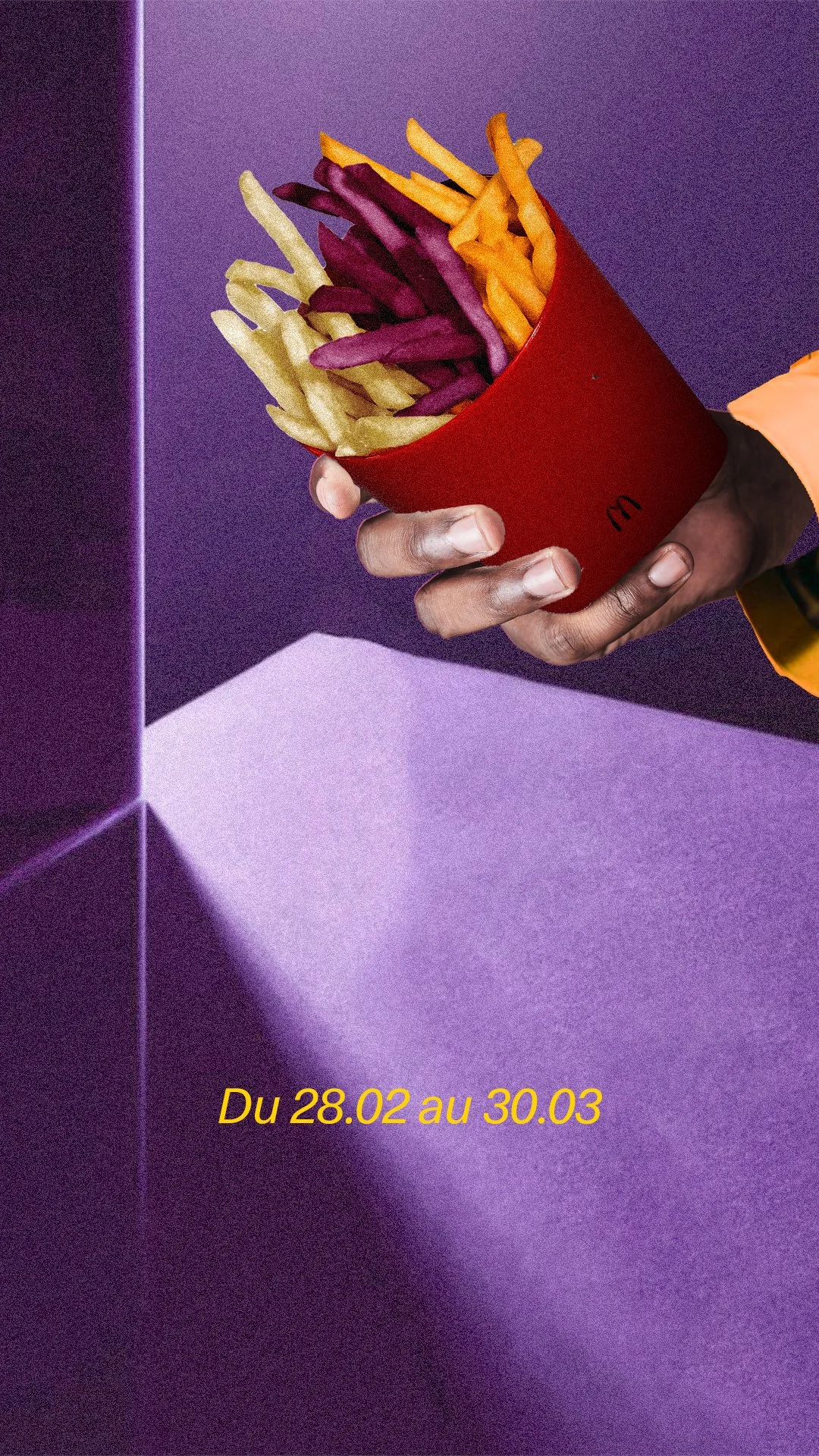 Une main tient un récipient rouge avec des frites de différentes couleurs, sur un fond violet. L'image comporte un texte en jaune "Du 28.02 au 30.03".