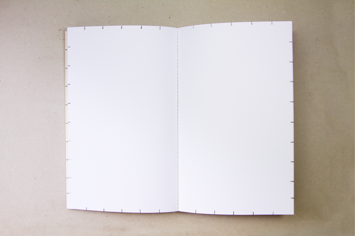 Un cahier ouvert avec des pages blanches, posé sur une surface beige.