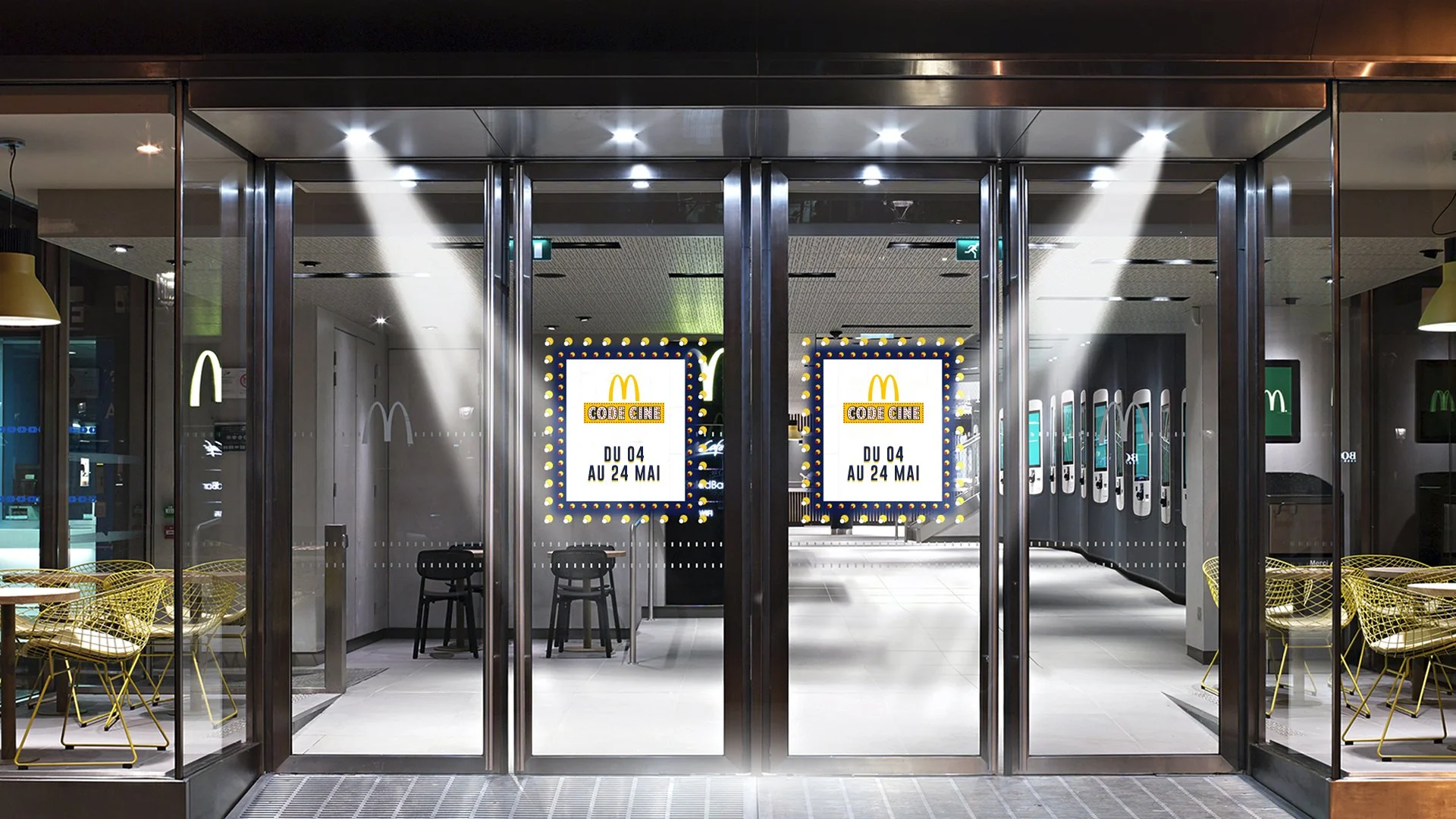 Entrée d'un restaurant McDonald's avec des portes en verre, affiches publicitaires pour une offre spéciale du 4 au 24 mai, intérieur moderne avec tables et chaises, et éclairage LED.