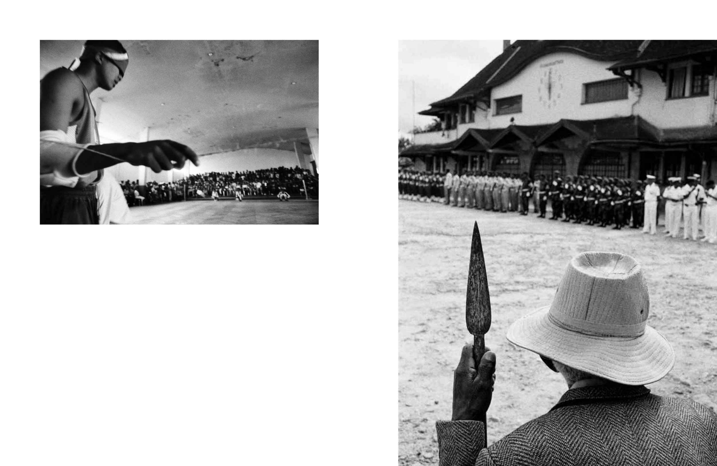 Une personne portant un chapeau de paille, tenant une arme, regarde un concours de sport ou de tir sur un terrain de sable, avec une foule au fond et des bâtiments en arrière-plan.