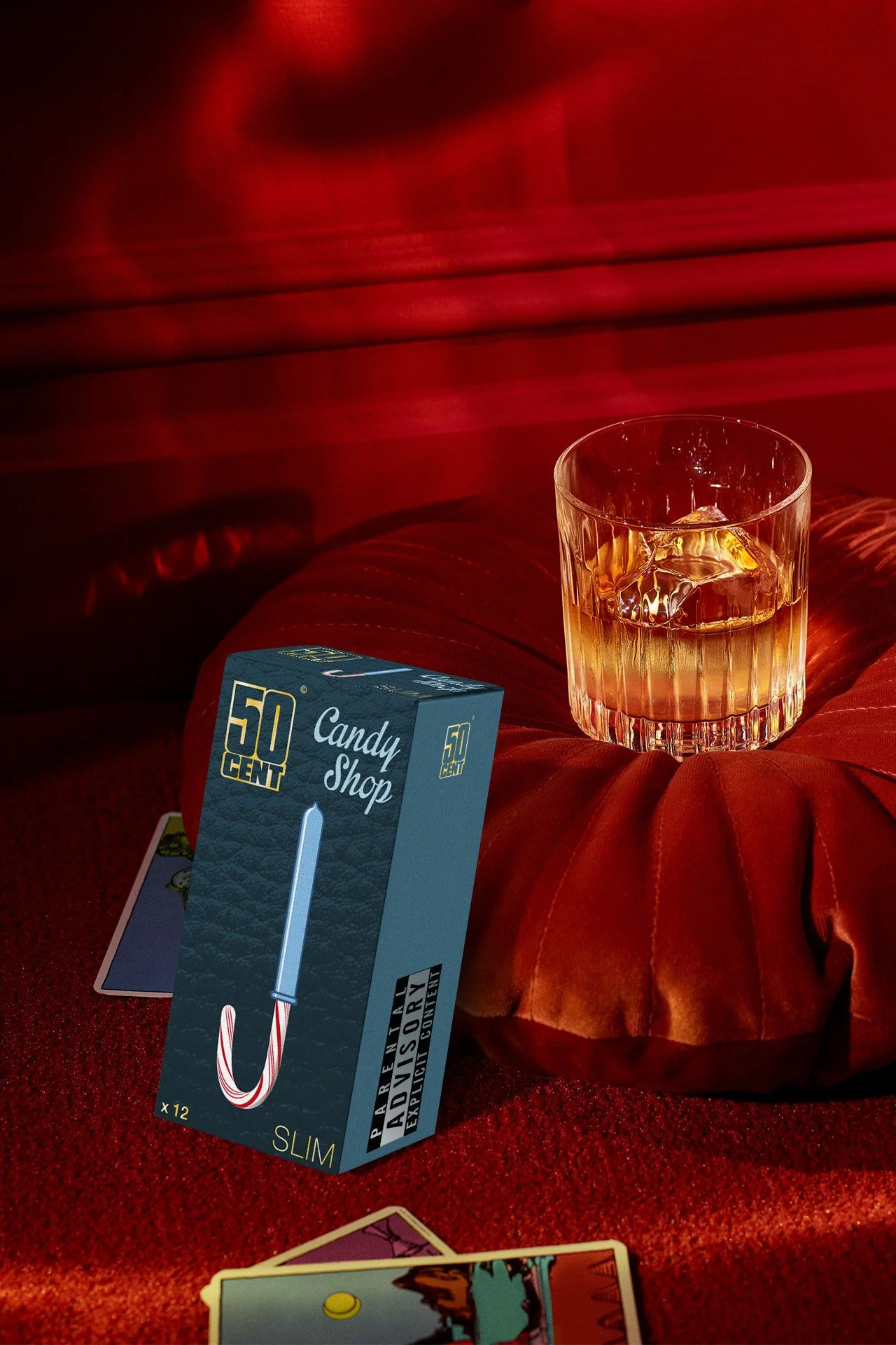 Verre de whisky avec glacé, boîte de cigarettes Virgin Slim, cartes de jeu sur un tapis rouge, éclairage rouge
