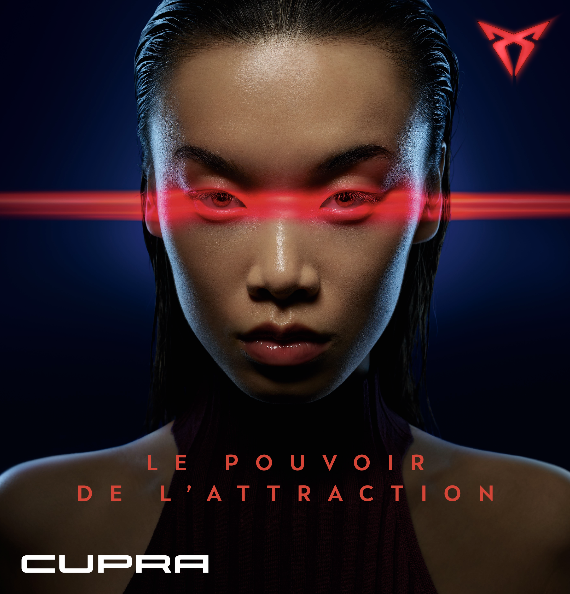 Premier plan d'une femme avec cheveux mouillés, yeux dirigés vers l'objectif, portant un haut noir, avec un arrière-plan sombre. Sur la moitié supérieure droite, un logo rouge en forme de triangle inversé avec une ligne au centre. Texte en rouge à la fin de l’image dit « LE POUVOIR DE L'ATTRACTIO » et logo blanc « CUPRA » en bas à gauche.