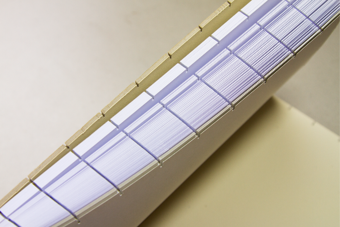 Un grand rouleau de papier thermique ou de tickets de caisse compactés, posé sur une surface beige ou grise.