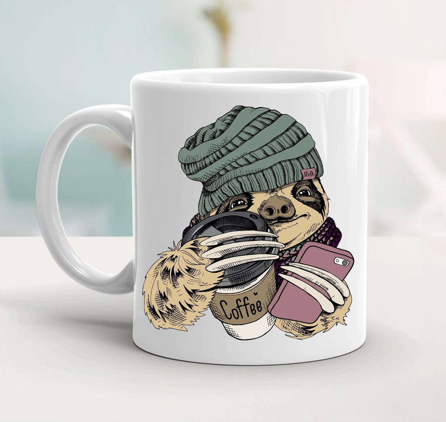 White ceramic mug with and image of a sloth wearing a beanie, holding a cup of coffee and a cellphone.