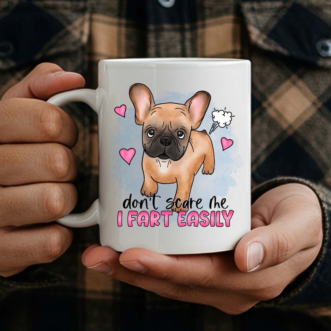 person holding Don’t Scare Me I Fart Easily French Bulldog humorous coffee mug, showcasing the design and comfortable grip, by Coffee and Moo.