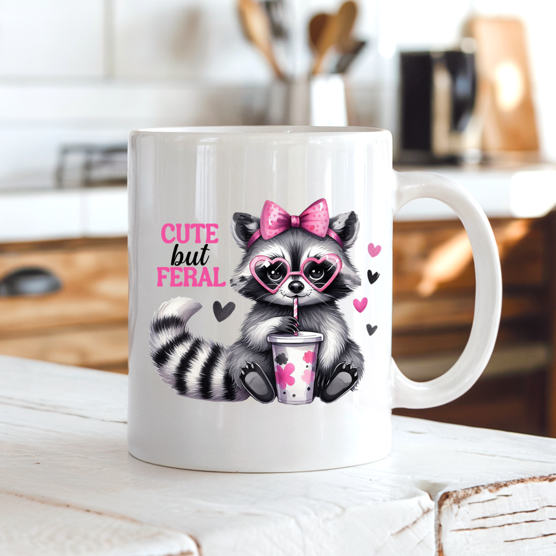 Cute But Feral Raccoon funny coffee mug on a country kitchen bench, adding humour to a rustic setting, by Coffee and Moo.