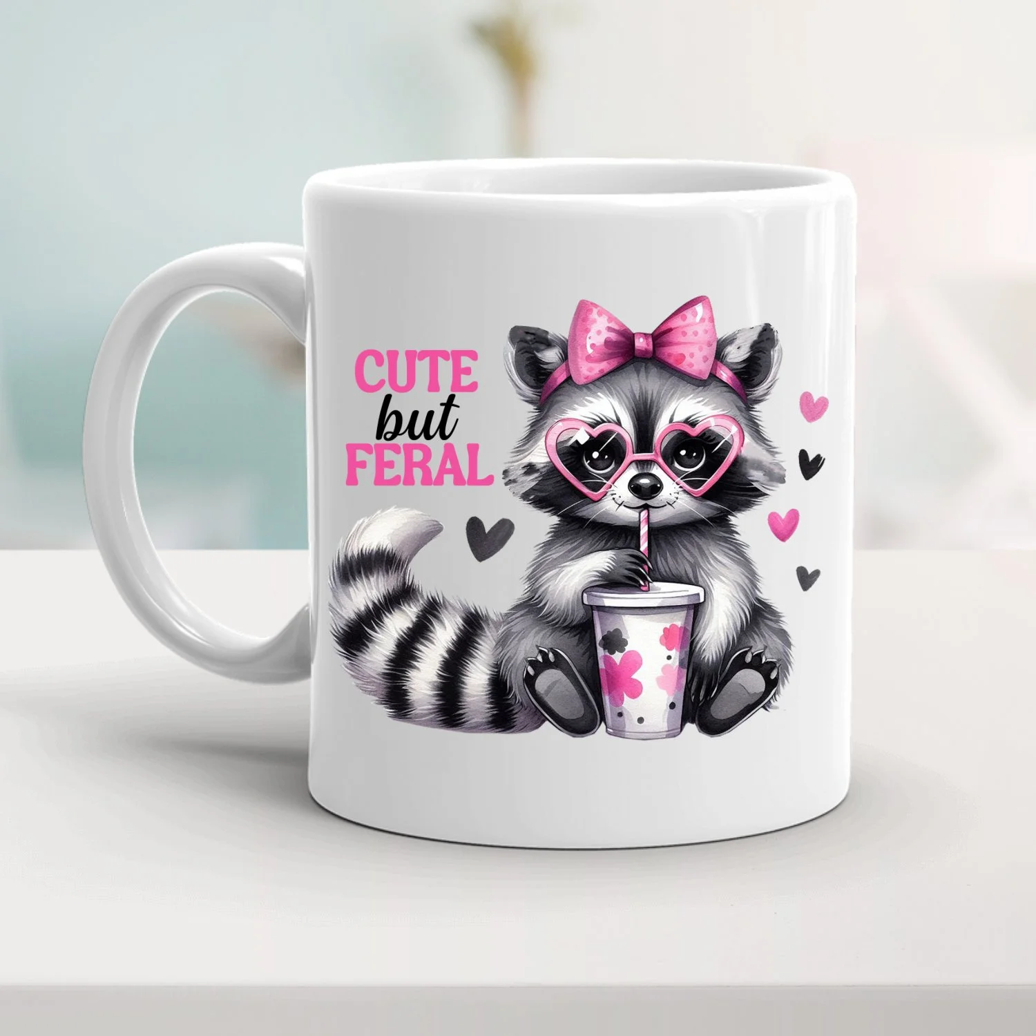cute mug with a picture of a cartoon racoon and the words cute but feral.