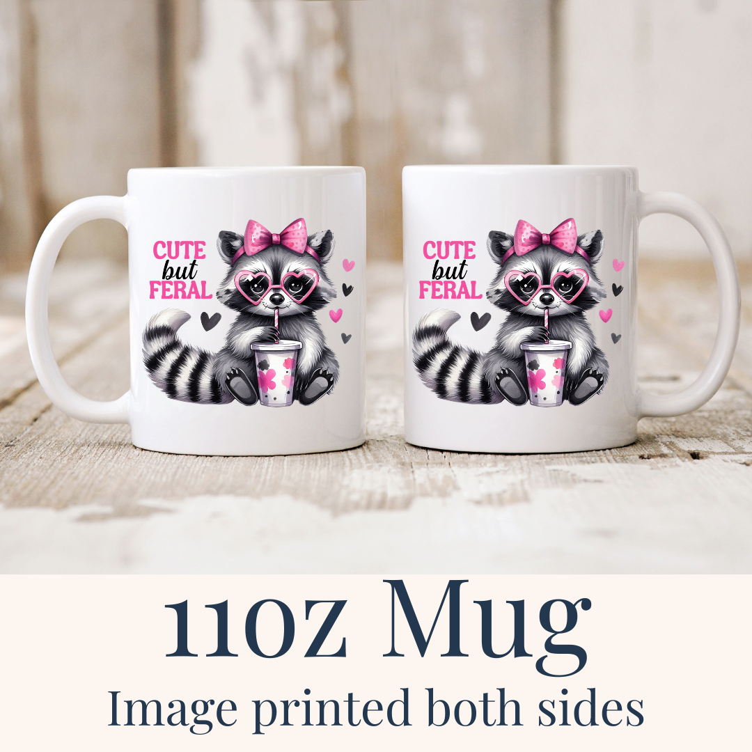 11oz Cute But Feral Raccoon ceramic mugs, with the "Cute but feral" design visible on both sides, from Coffee and Moo.