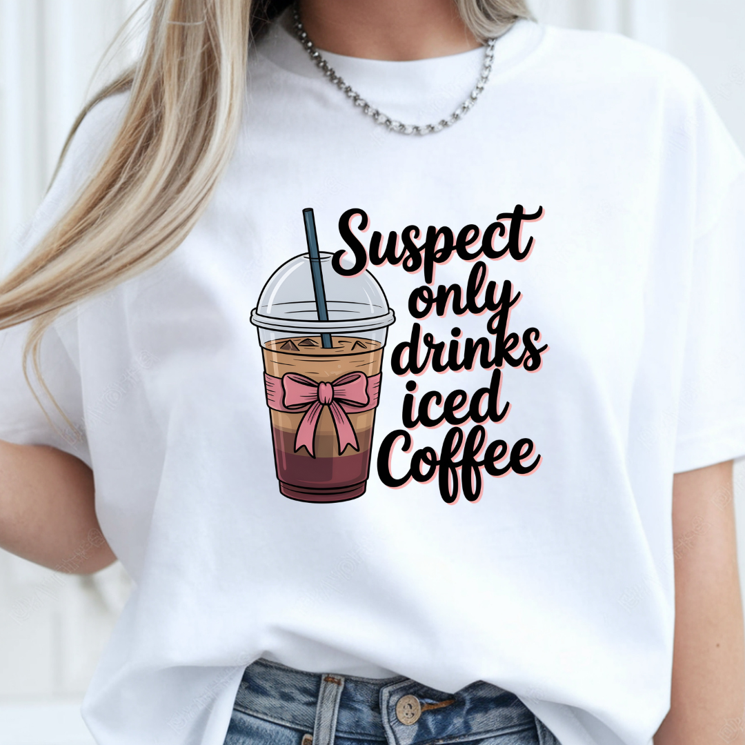 A white t-shirt with a cartoon illustration of a iced coffee and the text "Suspect only drinks iced Coffee" in black and pink lettering.