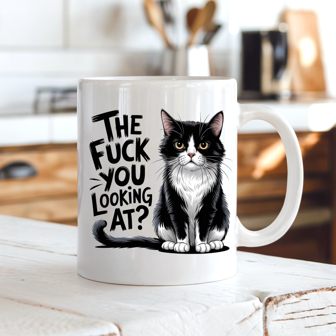 The Fuck You Looking At Cat funny coffee mug on a country kitchen bench, adding bold humour to a rustic setting, by Coffee and Moo.