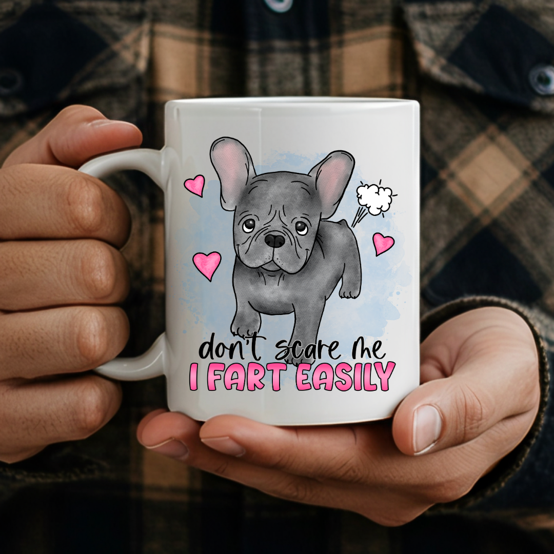 person holding Don’t Scare Me I Fart Easily French Bulldog humorous coffee mug, showcasing the design and comfortable grip, by Coffee and Moo.