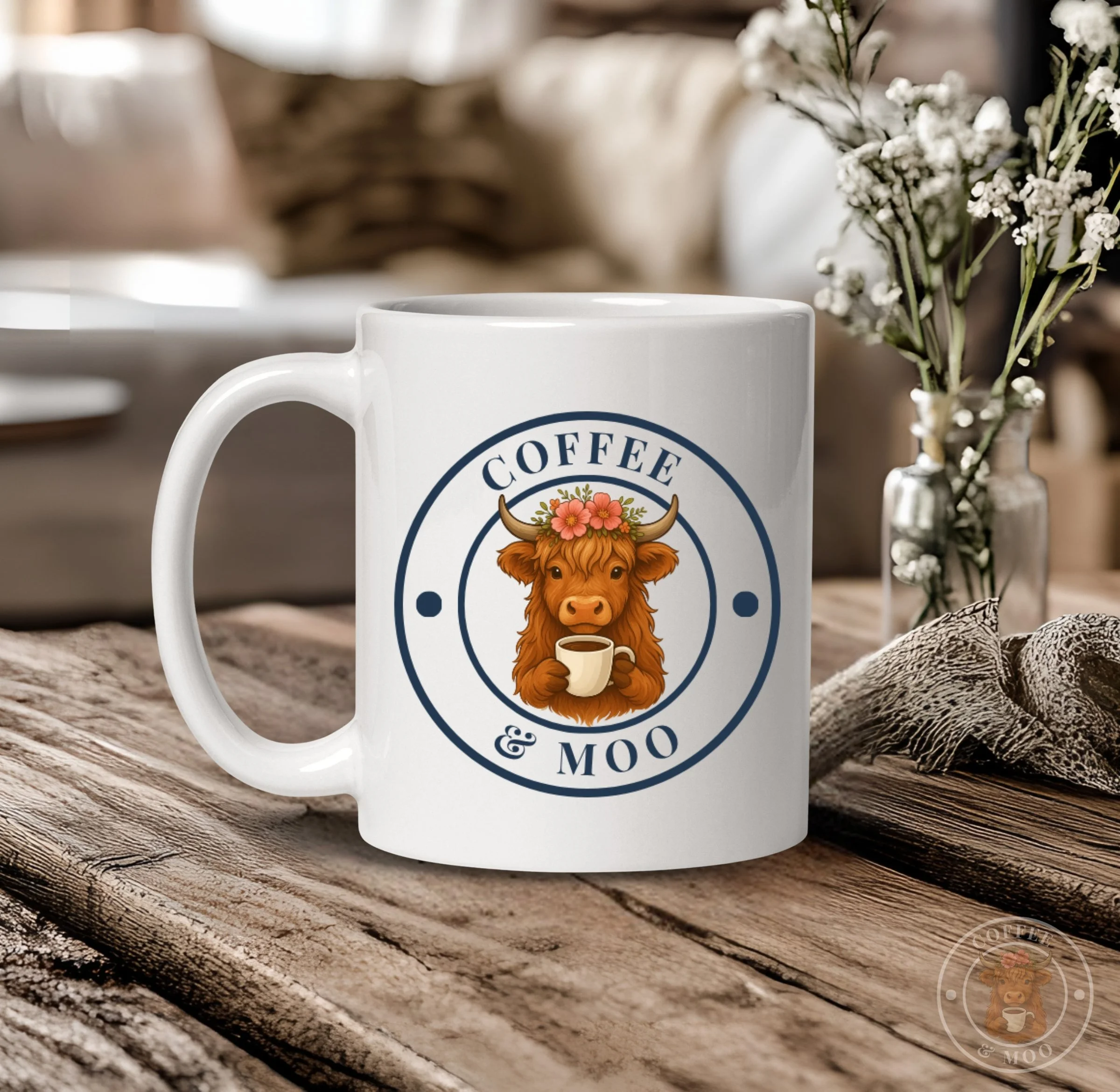 A white coffee mug on a rustic wooden table with a design of a cartoon highland cow wearing a flower crown, holding a coffee cup, and the words "Coffee & Moo" around the cow's head.