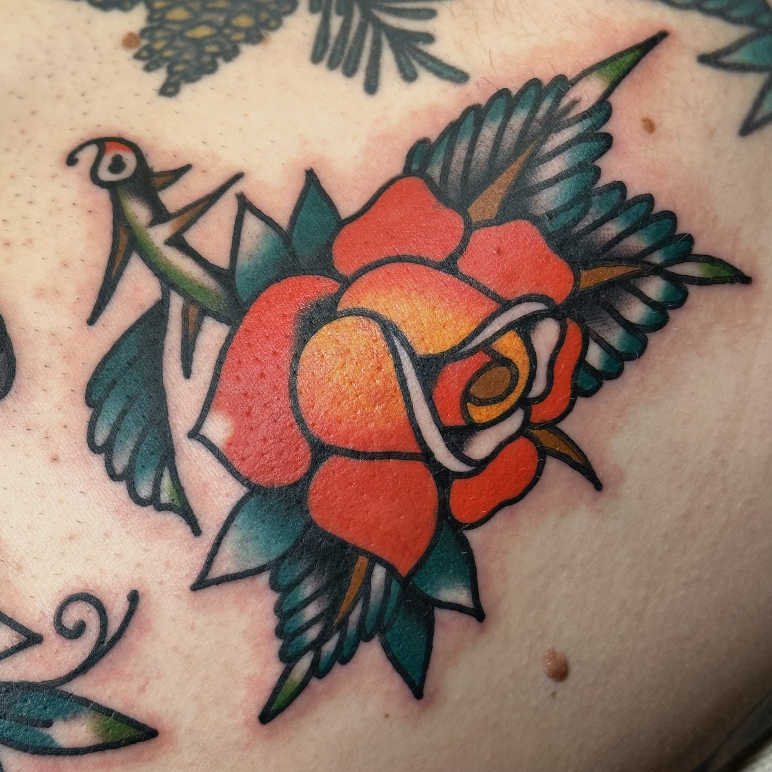 Colorful tattoo of a rose with green leaves on skin.