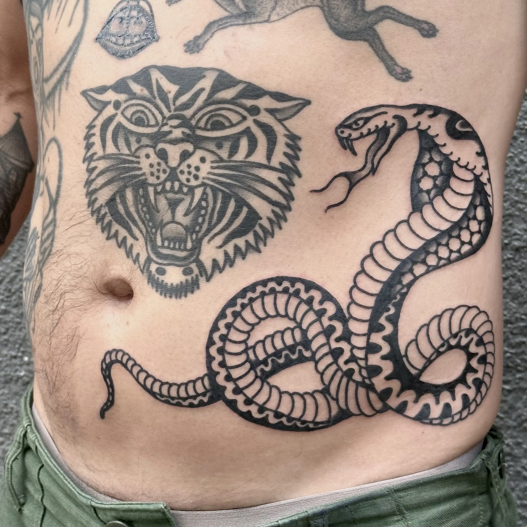 Tattooed chest featuring a large tiger face, an aggressive snake, and a partially visible arm tattoo.