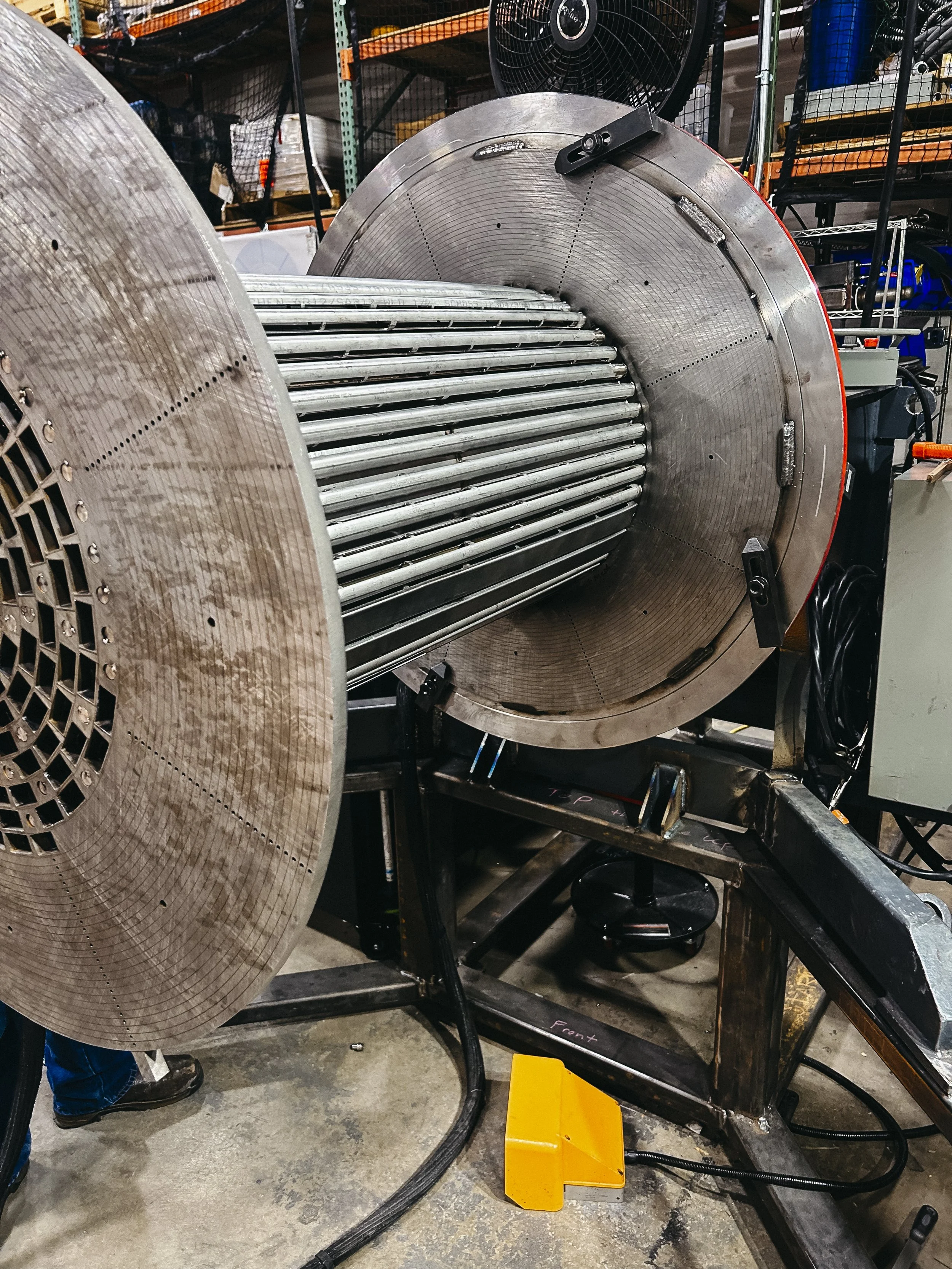 A large industrial wheel with multiple metal rods inside, mounted on a metal frame in a workshop.