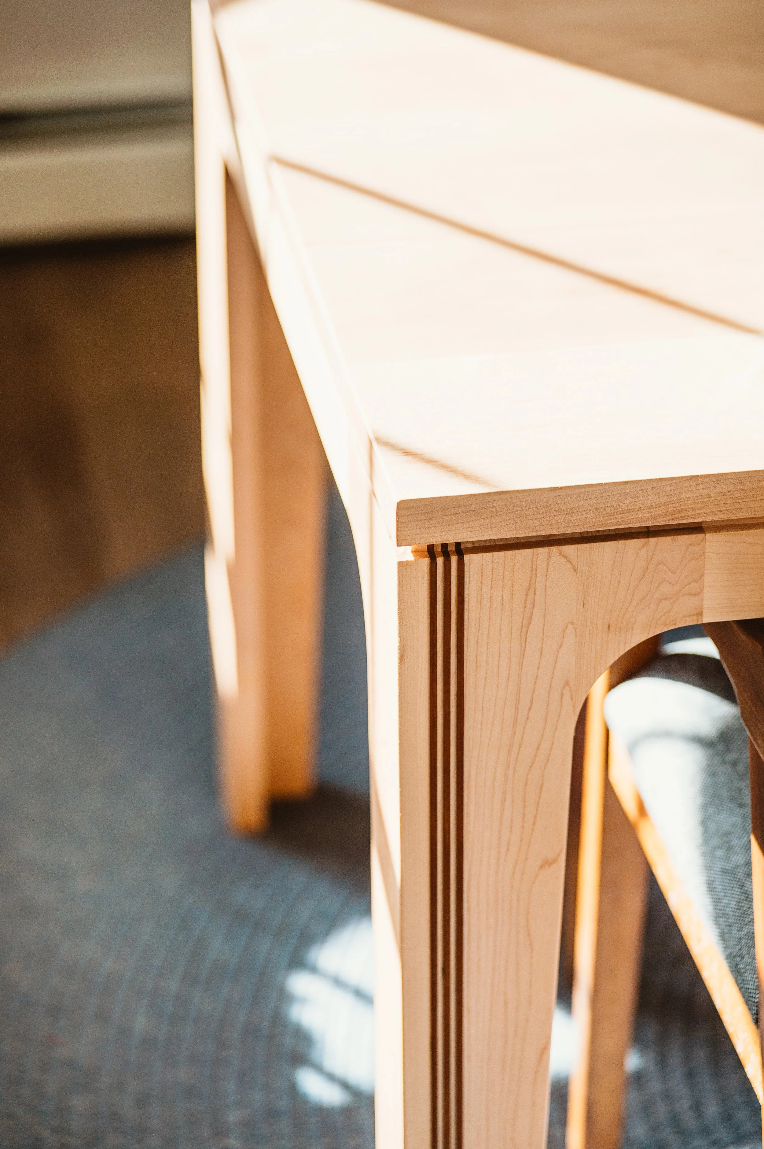Raised cherry inlay detail on maple dining table