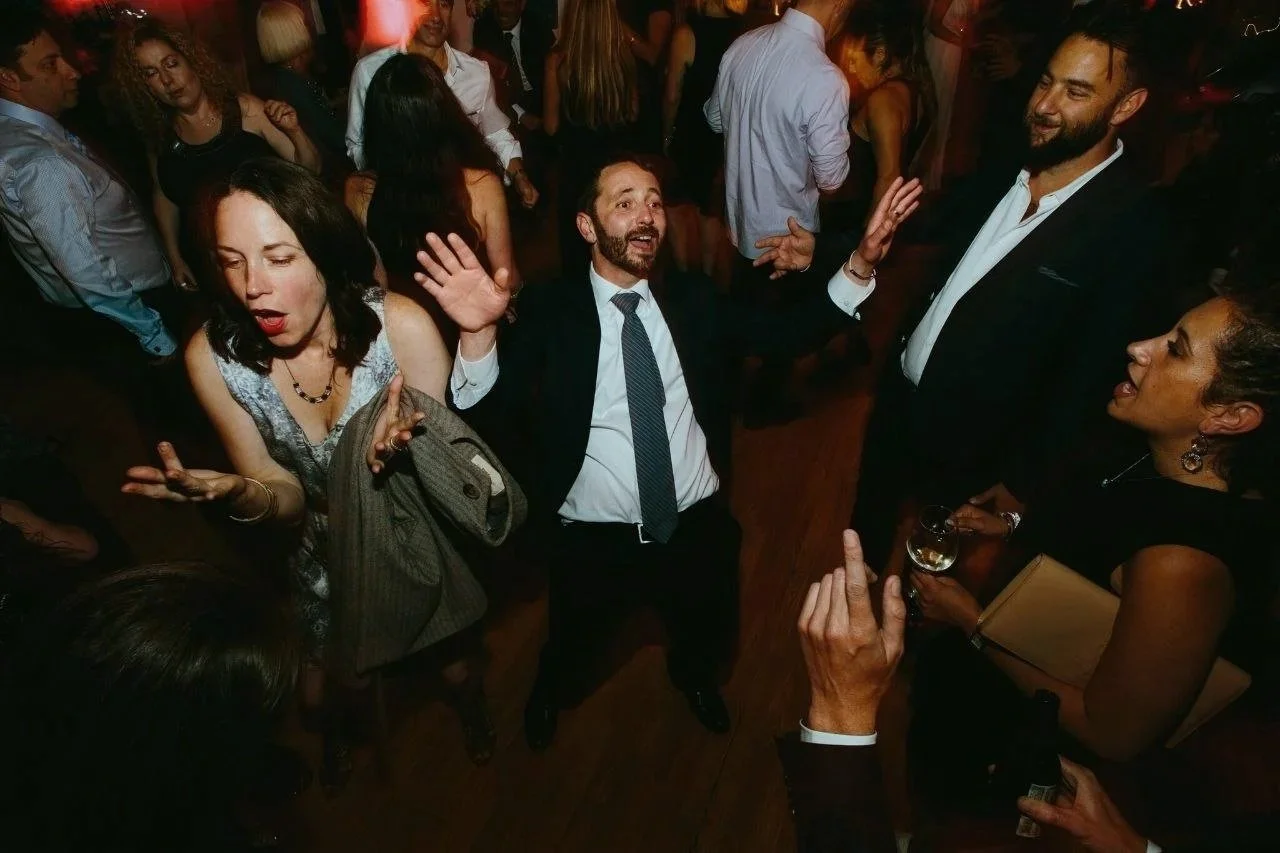 People dancing and socializing at a party or celebration in a dimly lit venue.